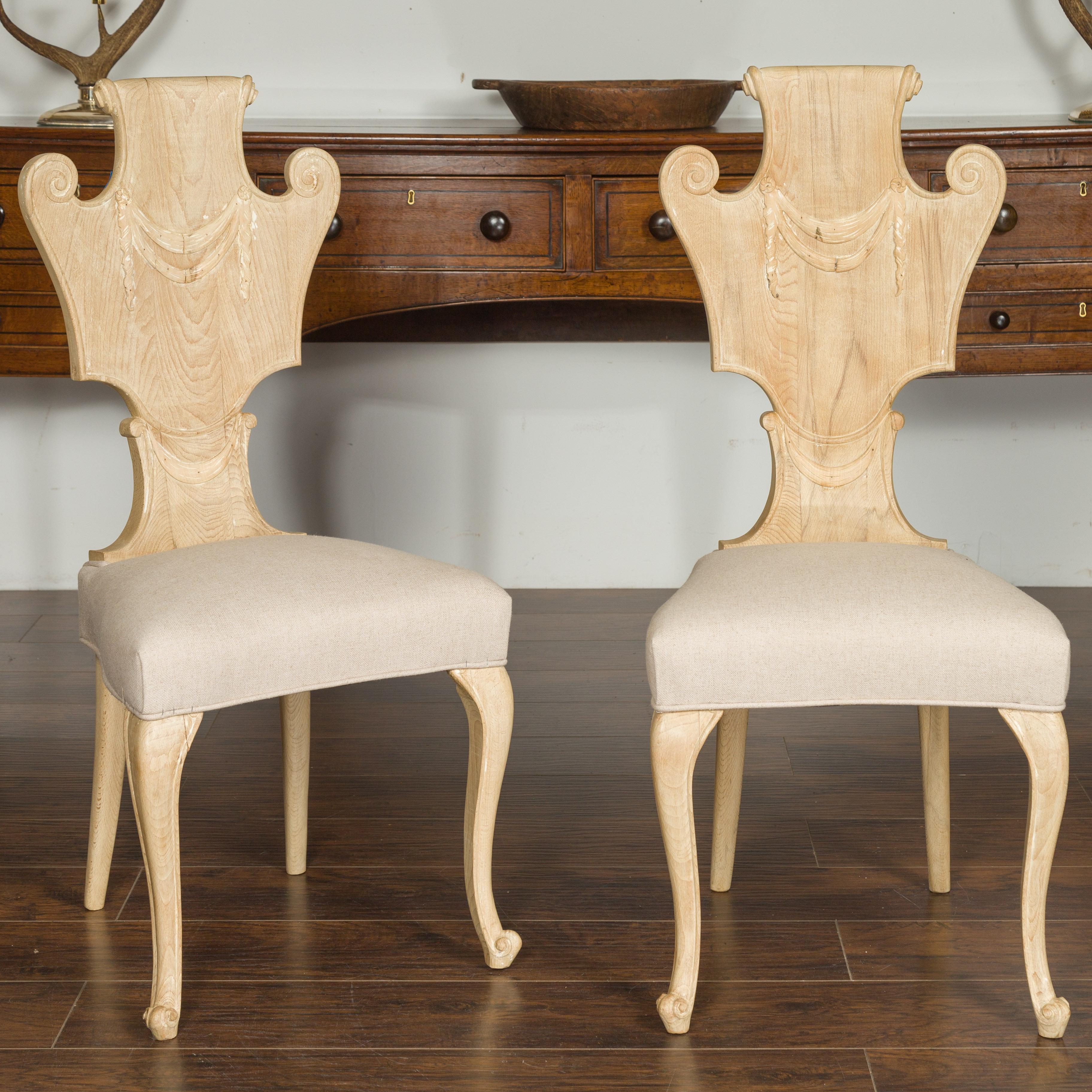 A set of six vintage carved Italian bleached walnut dining room side chairs from the mid-20th century, with scrolling backs and new upholstery. Born in Italy during the midcentury period, each of this set of six side chairs features a captivating