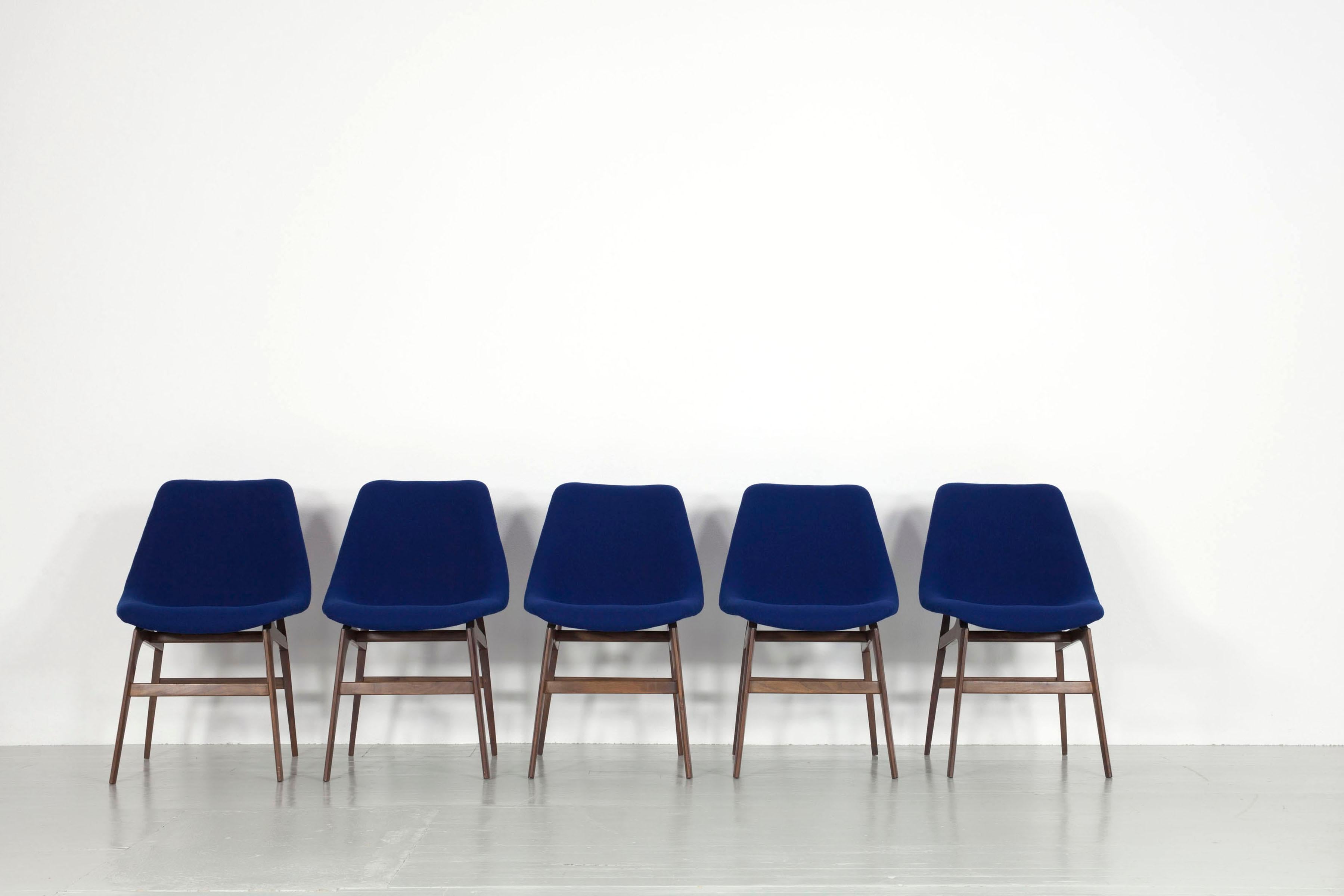 This set of six chairs was made in Italy in the 1960s and marketed by the Busnelli di Meda company. The sturdy teak chair frames show signs of wear. The seat consists of a fibreglass shell upholstered in foam with a dark blue cover. The upholstery