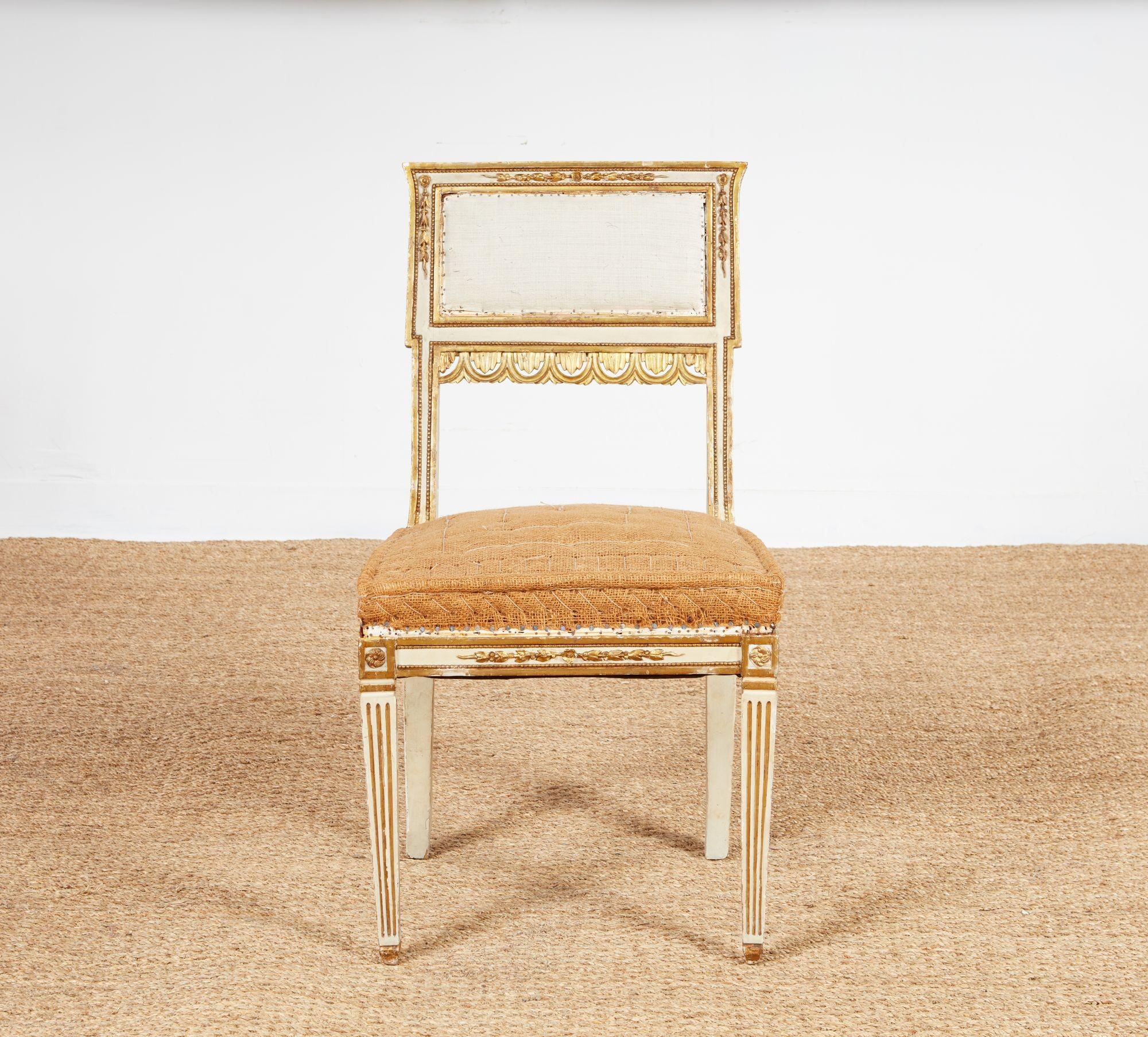 A set of six early 19th century neoclassical gilt and gesso decorated dining chairs. Upholstered rectangular geometric backs featuring stepped sides and flared tops outlined in gilt with inset gesso and foliate gilt ribbons, and decorative leaf