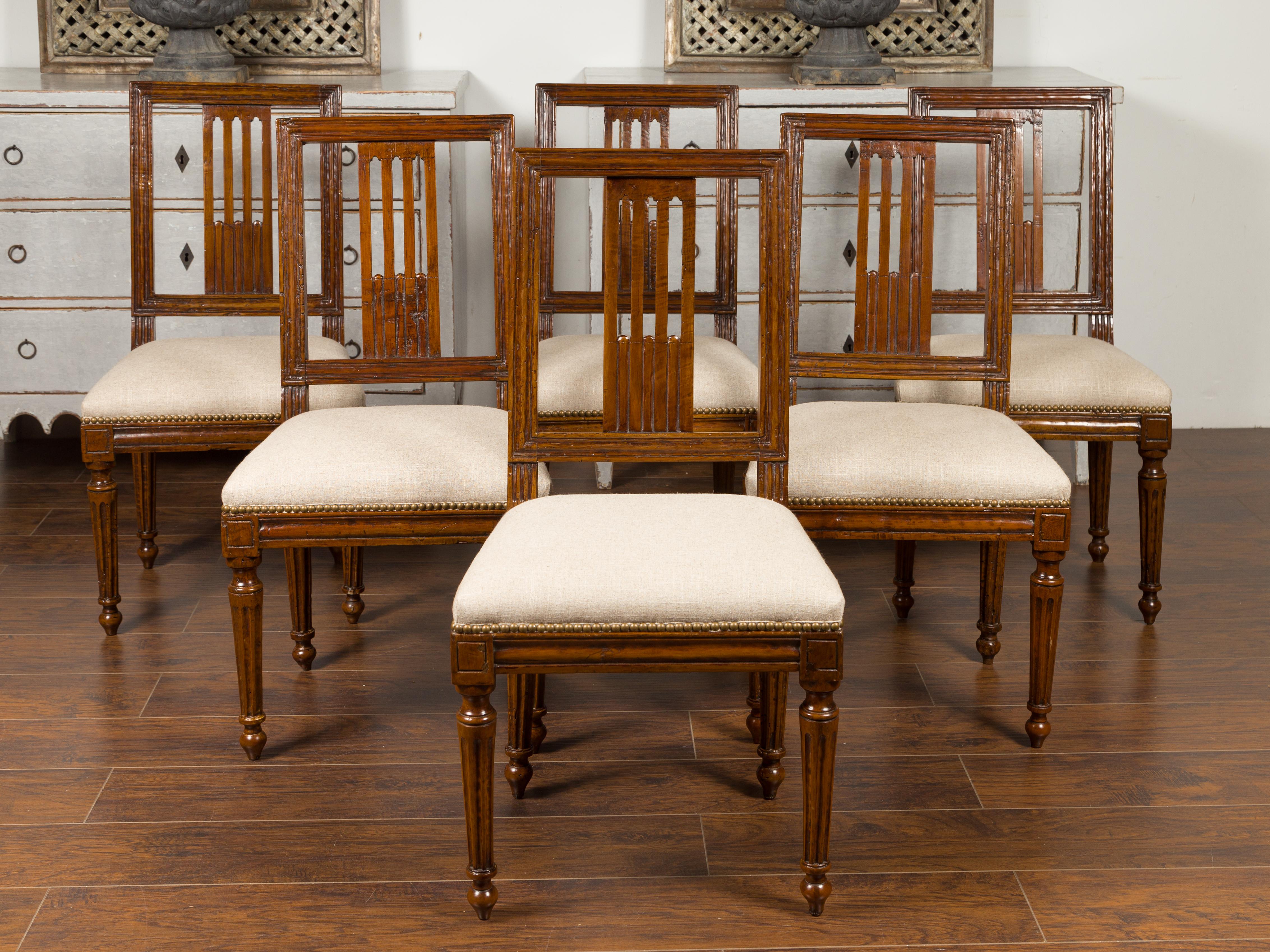 A set of six Italian oak dining room side chairs from the late 19th century, with pierced backs, fluted legs and upholstery. Born in Italy during the second half of the 19th century, each of this set of six oak side chairs features a slanted back