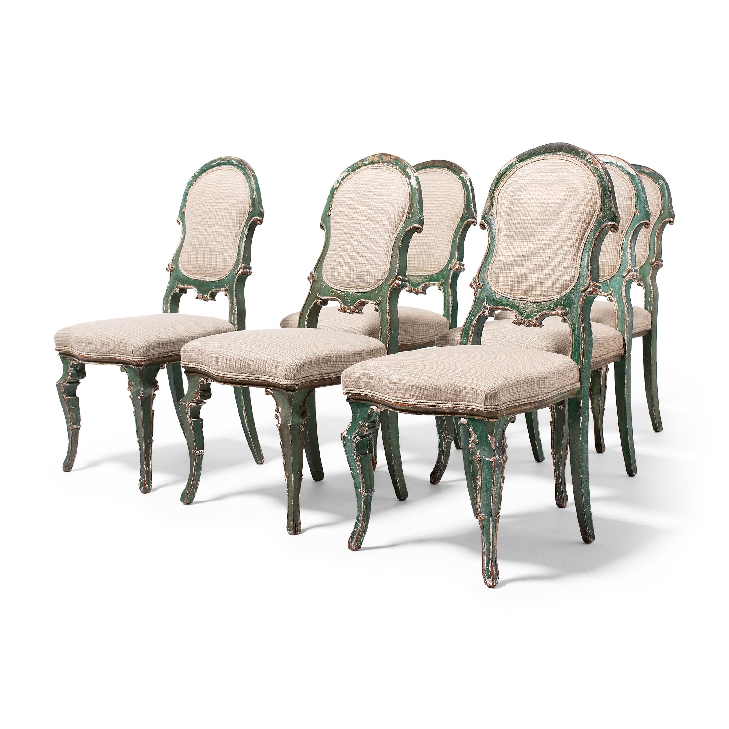 This set of six upholstered dining chairs wonderfully recreates the delicate, feminine seating of 17th and 18th century European furniture, incorporating design elements of Venetian Rococo and Louis XV. Dated to the early 19th century, the chairs