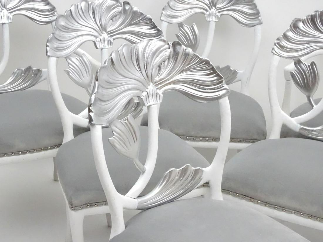 Set of six, these Italian made dining chairs include 2-arm and 4-side. These chairs feature wood construction in silver gilt and white lacquer finish.
Each with a large floral carving within an open oval back. The seats are upholstered with grey