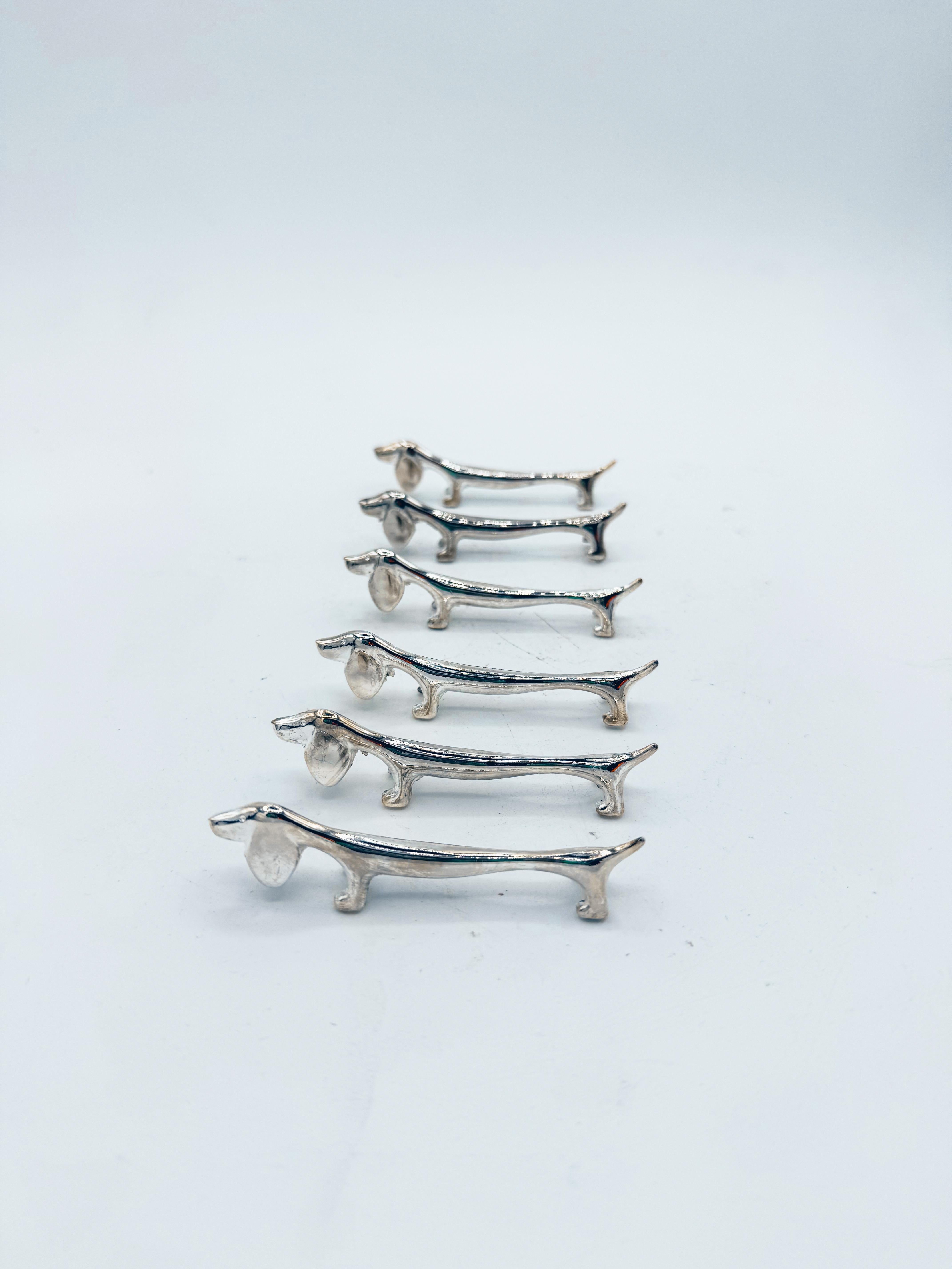Ein außergewöhnlicher Satz von sechs versilberten Dackel-Messerhaltern aus der italienischen Mitte des Jahrhunderts, exquisit gegossen in langgestreckten, modernistischen Formen, die den unverwechselbaren Charme des Dackels mit raffinierter