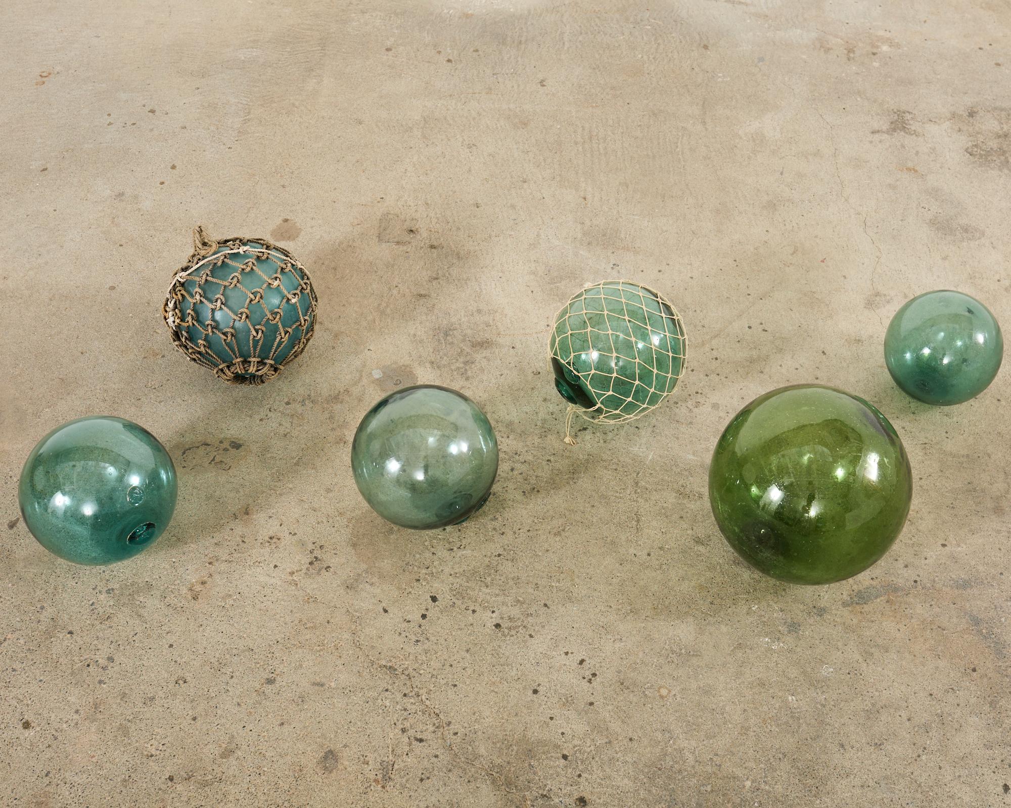 Large collection of six Japanese fishing floats or net buoys in rare large sizes. The hand-blown glass orbs measure from 9 inches (2) 10 inches (3), and one 14 inch float. The glass orbs have lovely jewel tones with two having a rope netting still