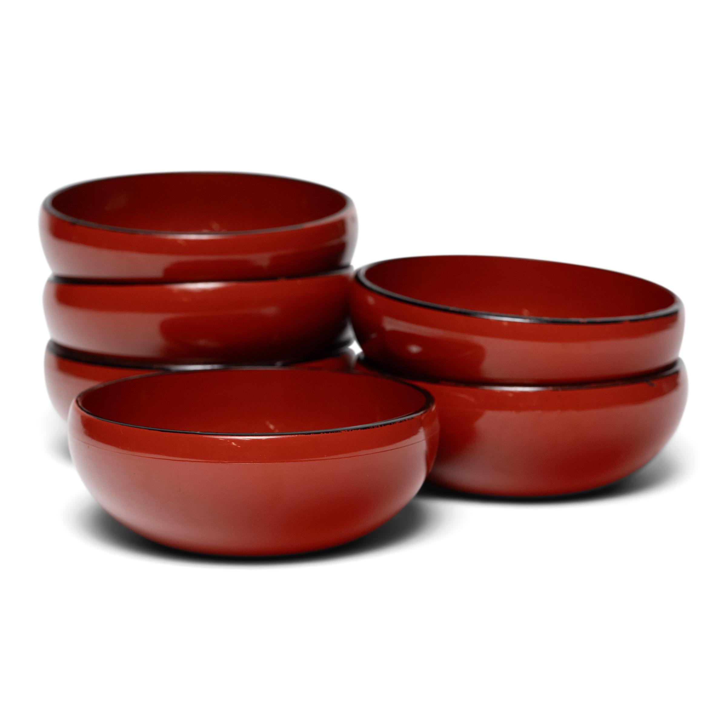 Lightweight and compact, this set of six small bowls is an example of the classic Japanese lacquer bowls used daily for food and drink. Each bowl is simply shaped with a rounded underside that forms a continuous, uninterrupted line. A glossy red