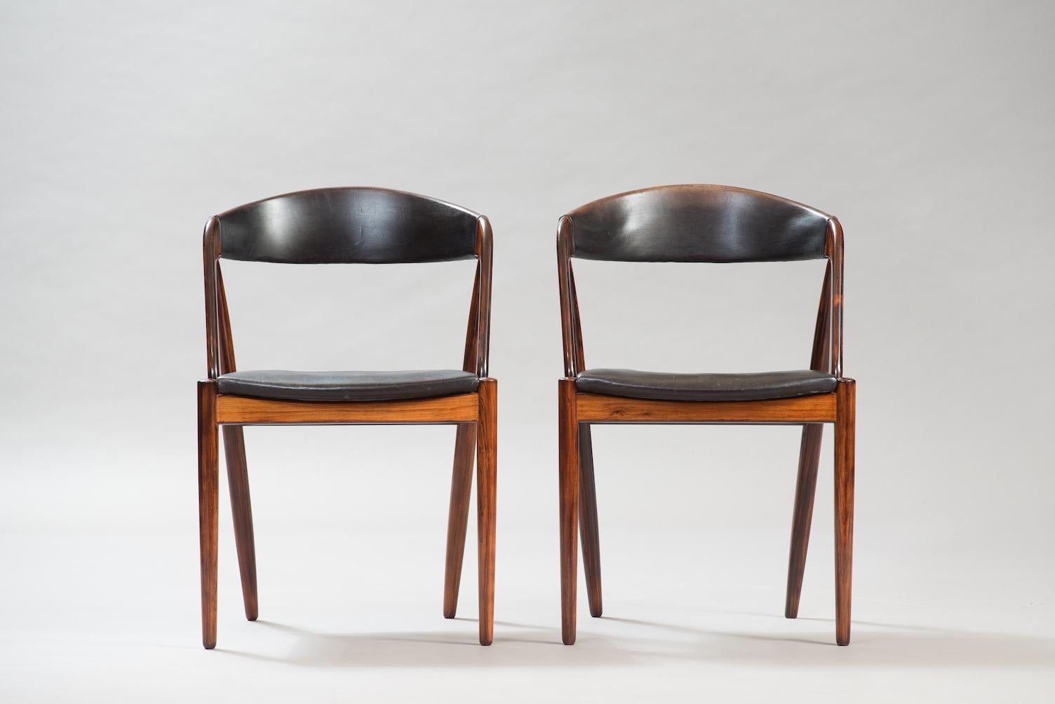 Set of six massive rosewood curved back dining chairs upholstered in the original black leather, model 31.