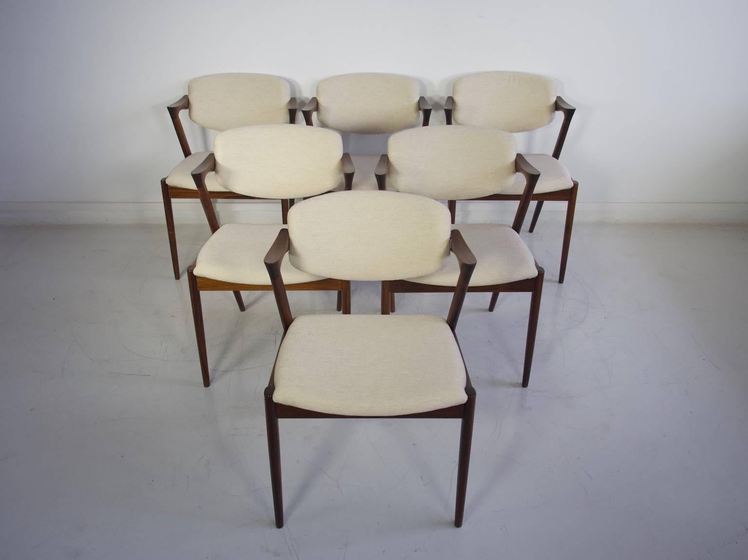 Six armchairs, model 42, designed by Kai Kristiansen. Rosewood frame, back with tilt function. Recently reupholstered with light color fabric. Designed in 1956-1957. Manufactured by Schou Andersen Møbelfabrik. At close inspection, a few chairs have
