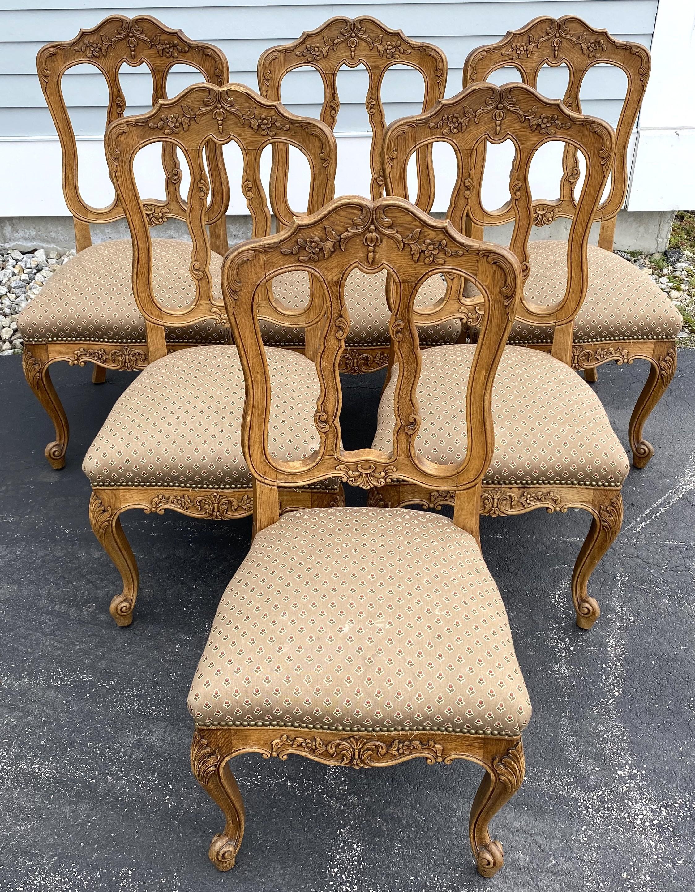 Un bel ensemble de six chaises de salle à manger de style Louis XV en chêne sculpté de rinceaux et de feuillages, avec une garniture de feuillages. L'ensemble date de la fin du XIXe siècle et est en très bon état général, avec quelques taches