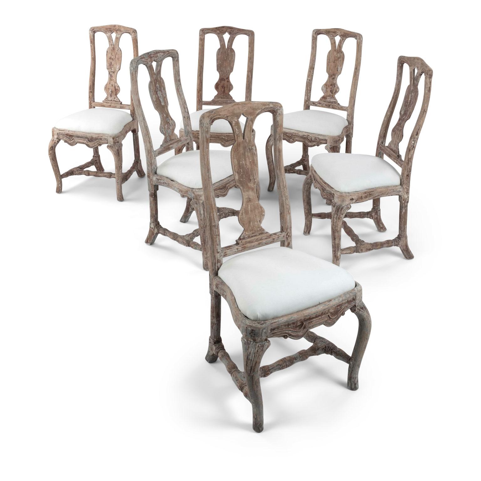 Set of six late baroque Swedish dining chairs, hand-carved circa 1730-1759. Originally gilded. Scraped finish with remnants of gesso, clay-red size and early layers of gray paint. Six sold together and priced $16,800 for the set.
