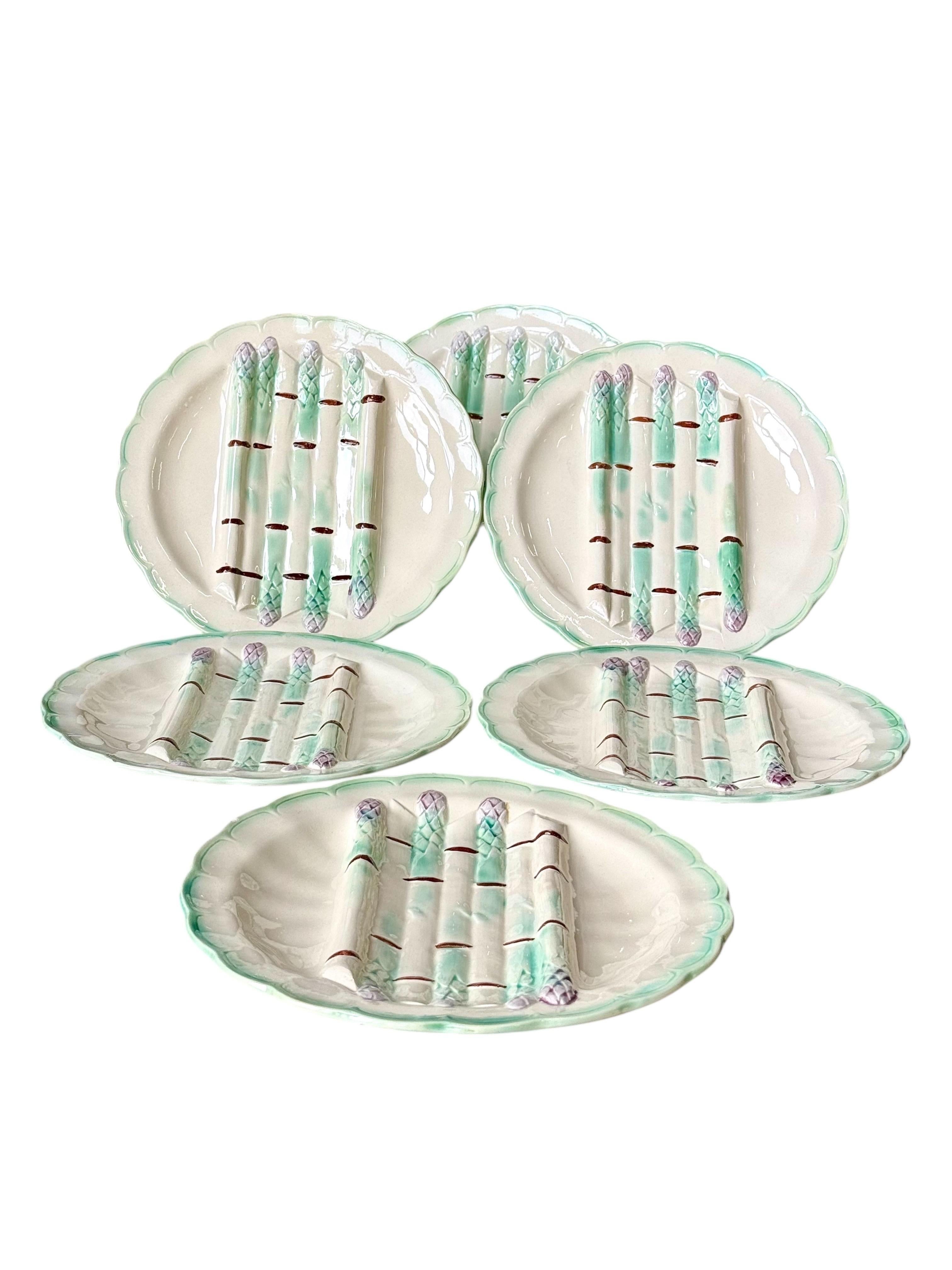 Dieser schöne Satz von sechs Longchamp Terre de Fer Spargeltellern ist ein reizvolles Beispiel für die französische Majolika-Kunst des 19. Jahrhunderts. Jeder Teller, der von der historischen Longchamp-Fabrik in Burgund hergestellt wird, trägt auf