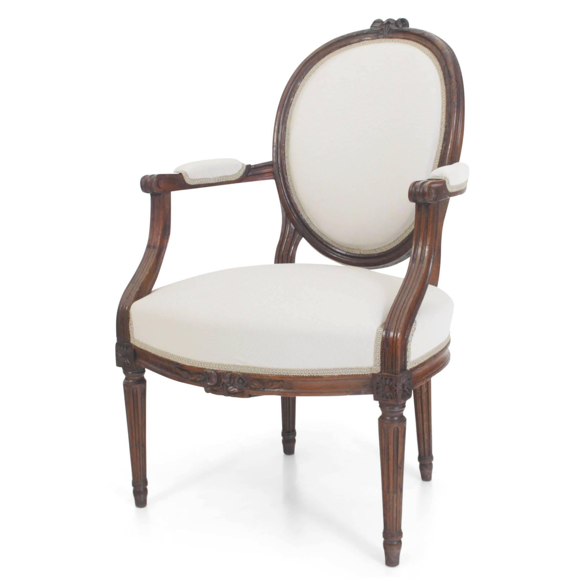 Set of six armchairs with fluted legs and cushioned seats, back and armrests. The armrests curve down elegantly and end on top of the front legs. The front rail and each medallion is decorated with carved rose-ornaments.