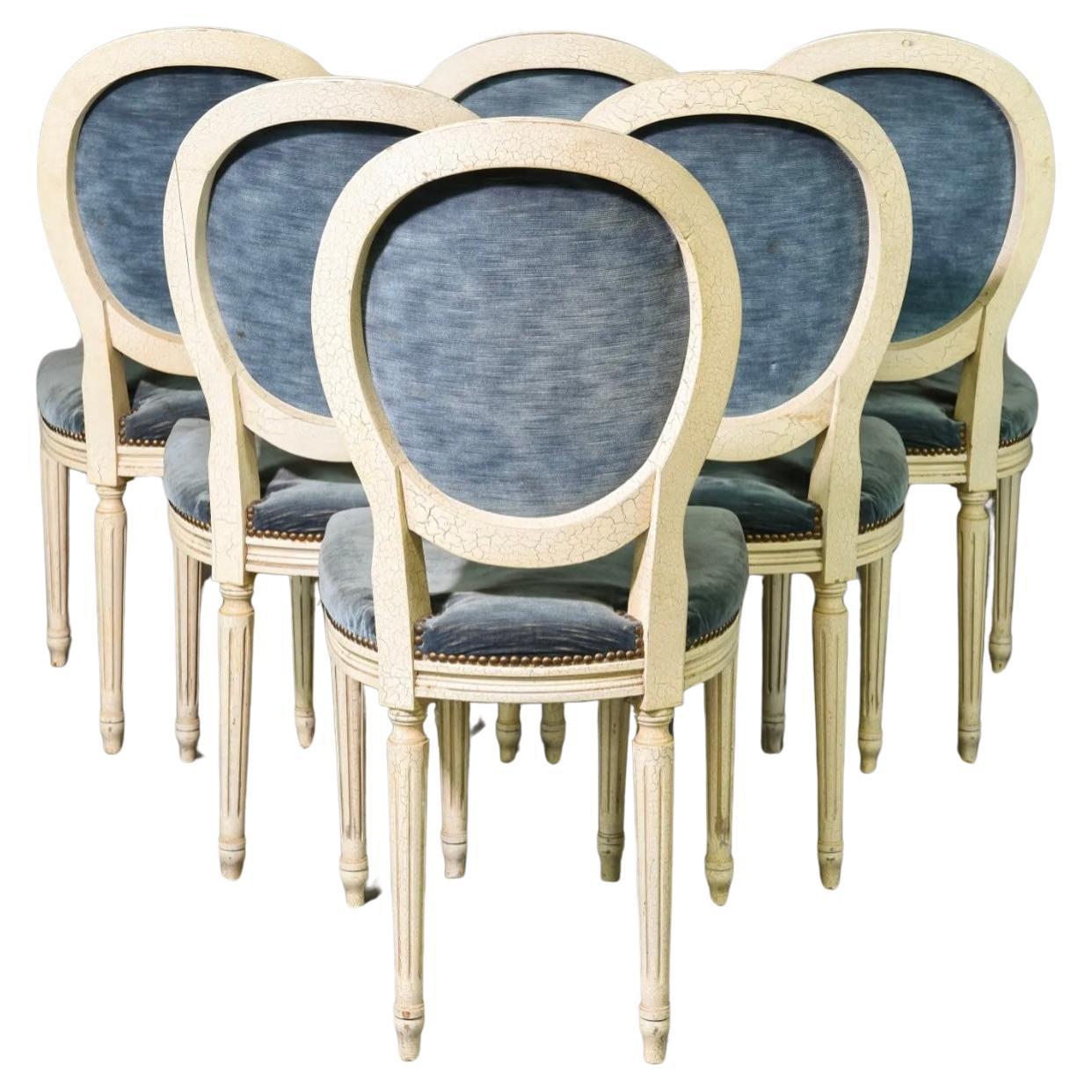 Set of 6 French Louis XVI Style Painted Balloon Back Chairs. Each chair features hand-molded frame with an oval-shaped medallion back, and are upholstered in soft blue fabric with brass-tack nail head trim. Chairs are supported by tapered fluted