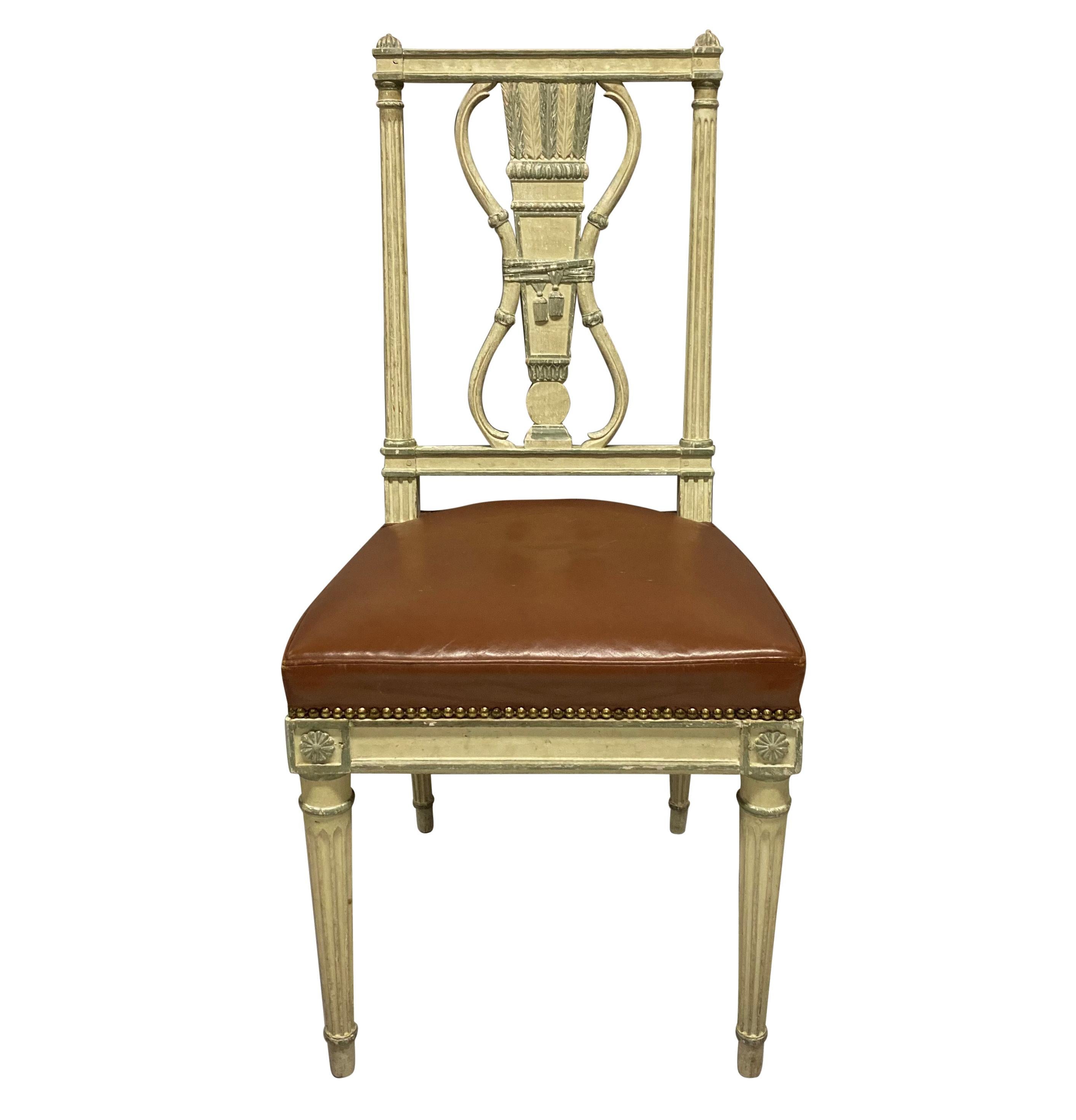 Un ensemble de six chaises de salle à manger de style Louis XVI peintes en crème et eau de nil. Les sièges en cuir fauve clouté sont en bon état général.