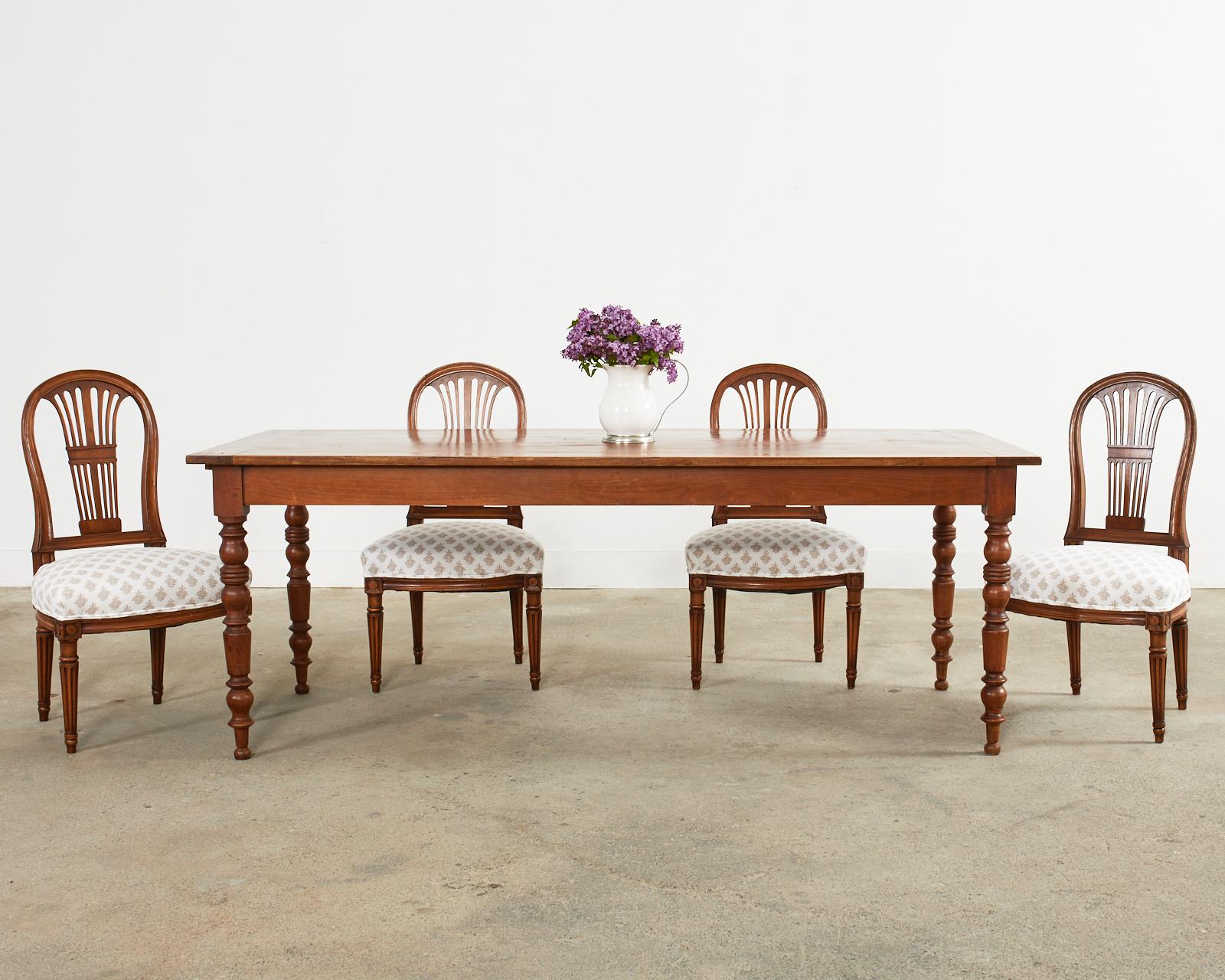 Distinctive set of six French dining chairs hand-crafted from walnut. The chairs feature a graceful balloon back in the grand Louis XVI style. The generous seats have been newly upholstered and the seat is supported by tapered and fluted legs. The