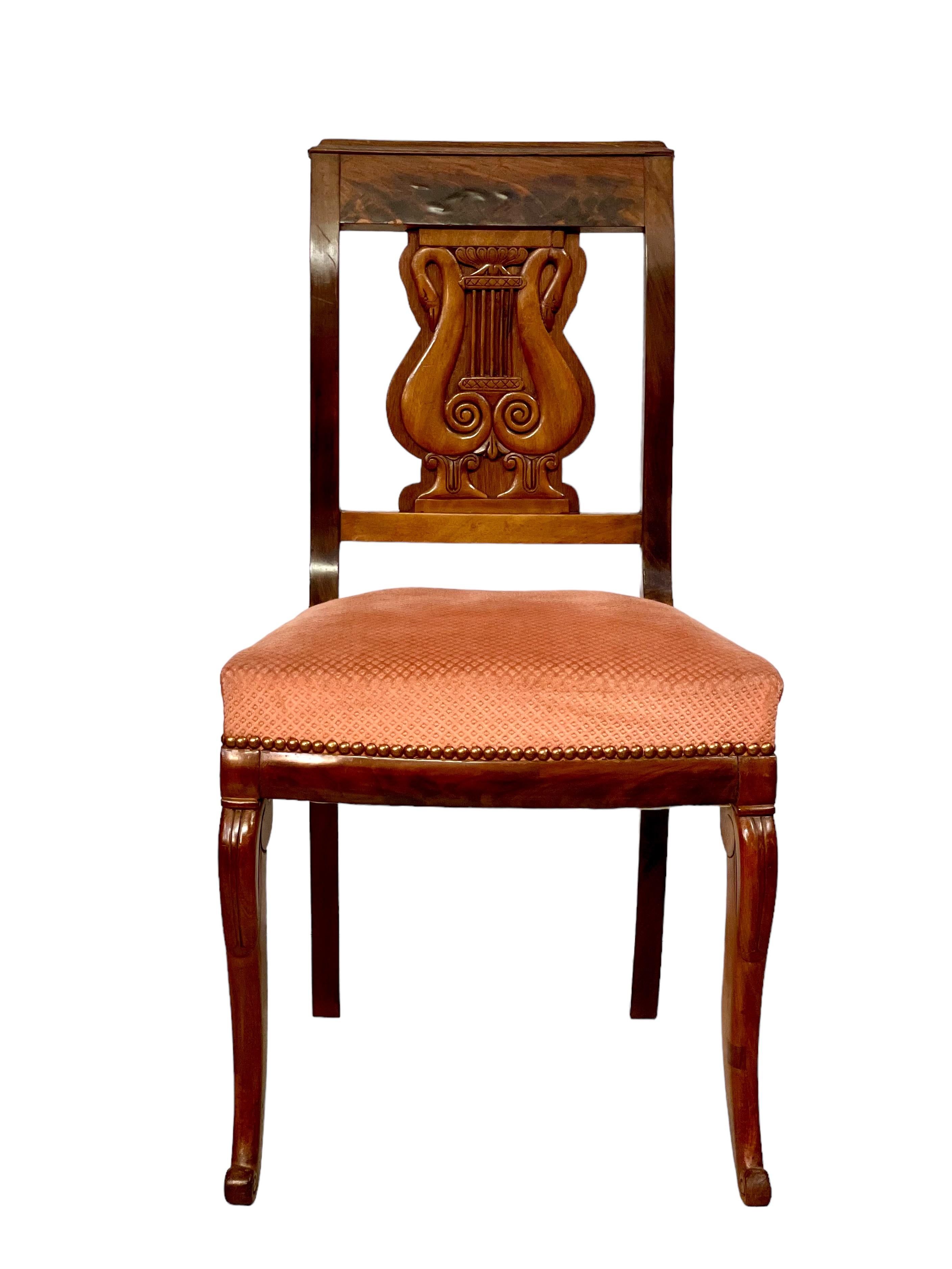 A set of six antique French dining chairs, dating from the Restoration period (early 19th century), each featuring an elaborately carved back in the form of a lyre. Crafted from fruitwood and fruitwood veneer, these chairs are each fitted with a