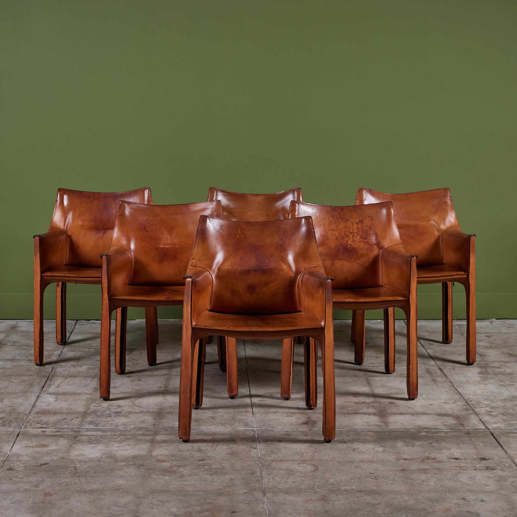 The iconic chairs designed by Mario Bellini for Cassina c.1970s, Italy, feature the original camel saddle leather which is wrapped atop the steel frames. This set of six armchairs are perfectly patinated. The back legs feature a black zippered