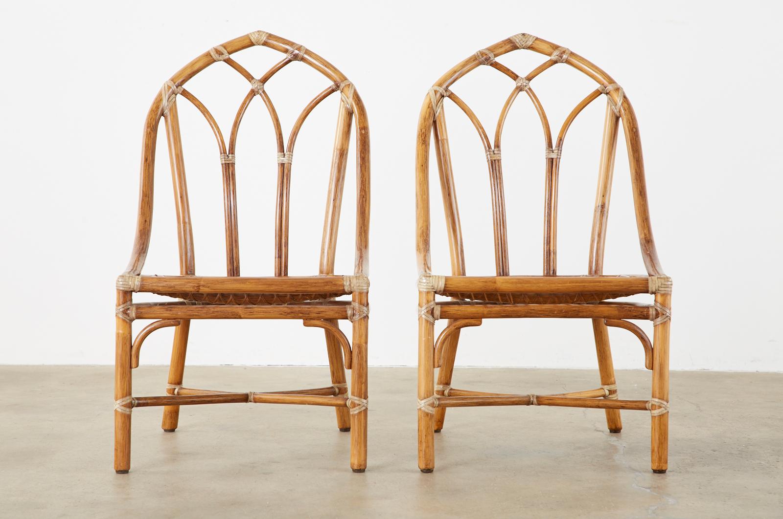 Stylish set of six genuine McGuire bamboo rattan dining chairs made in the California organic modern style. Set consists of two armchairs and four side chairs. Constructed from rattan poles lashed together with leather rawhide laces. The backs have