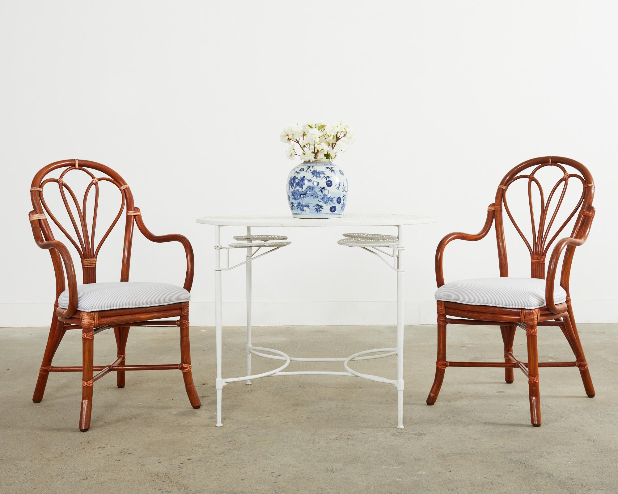 Exceptional set of six rattan dining armchairs made in the California coastal organic modern style by McGuire. The chairs feature a bentwood rattan frame with gracefully curved arms conjoined to an oval back with a fan shaped splat. The joints are