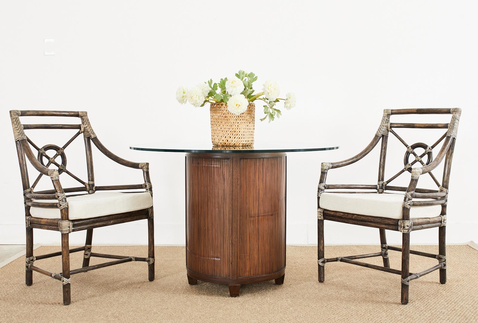 Remarkable set of six McGuire rattan dining chairs consisting of four armchairs and two side chairs. Bespoke set featuring an intentionally aged dark lacquer finish on the rattan with contrasting light cream colored leather rawhide laces. Designed