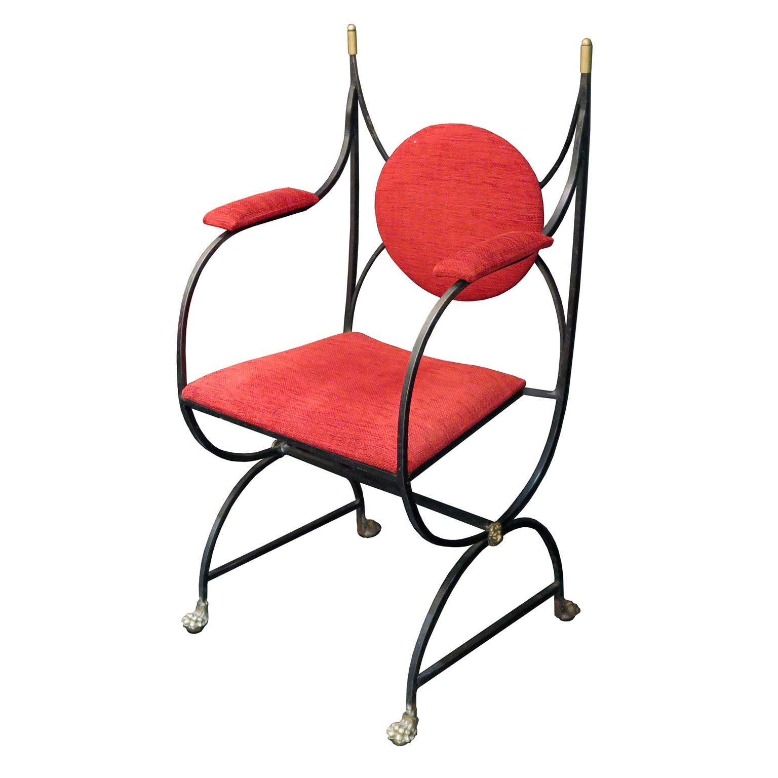Set of six midcentury chairs in black wrought iron with brass claw feet and lion heads on legs. Brass finials decorate the top frame of the chairs. Upholstery consists of rounded backs and square seat cushions in a red fabric. There are five side