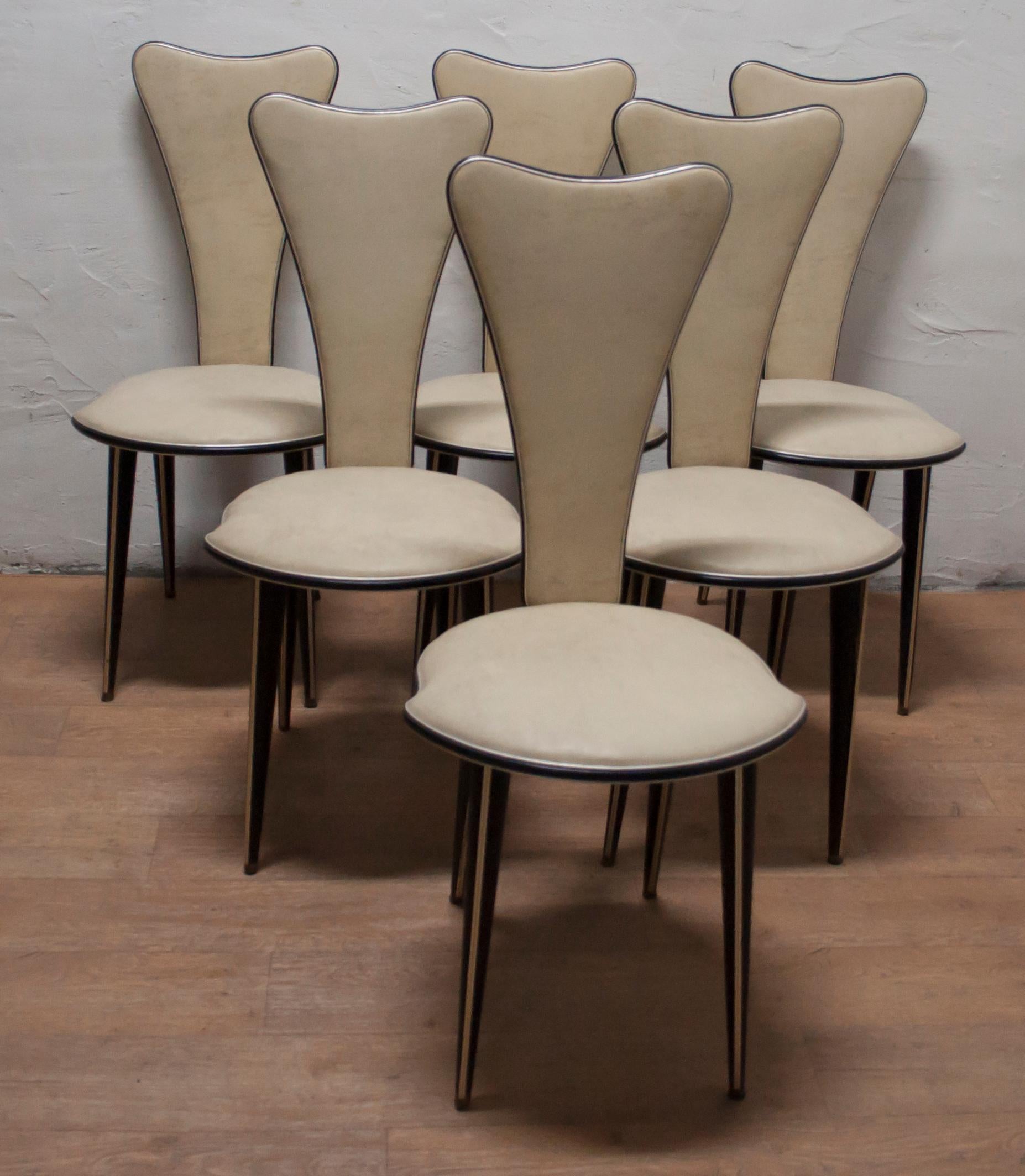 Six chairs designed by Umberto Mascagni of Bologna in the 1950s. The main body structure is made of solid European wood, covered in cream-colored vinyl with anodized aluminium. Even the legs are covered in black vinyl! Very attractive chairs,