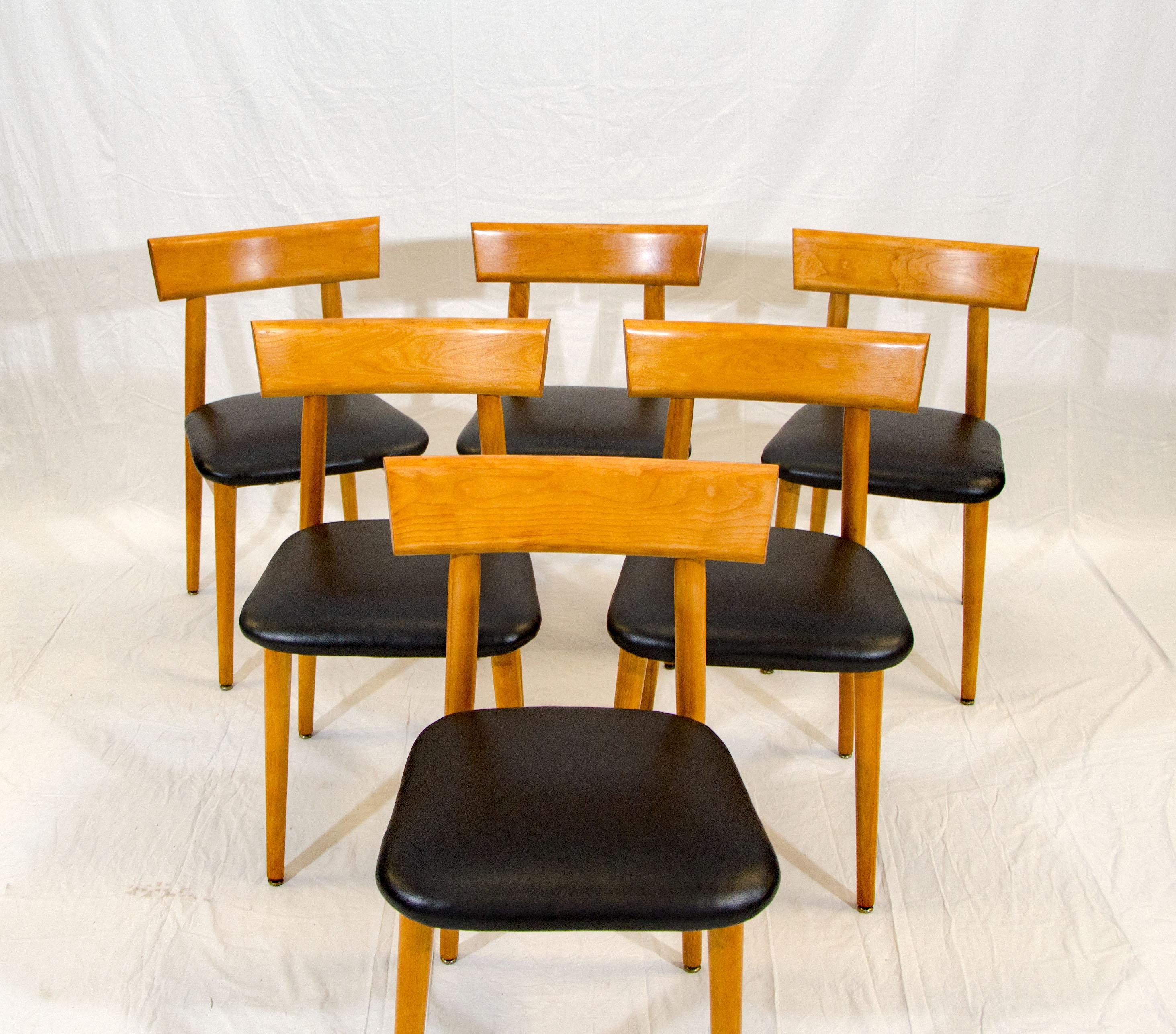 This set of six blond maple dining chairs are manufactured by Conant Ball and designed by either Russel Wright or Leslie Diamond. The black vinyl seats are original, but upholstery could be done easily, as the seats detach from the frames.