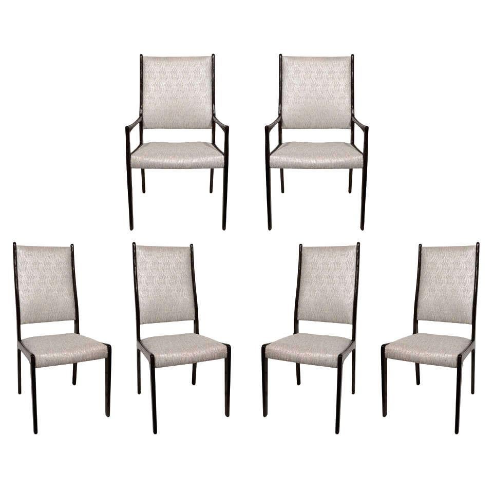 Set of Danish Modern highback dining chairs with ebonized teak wood frames. Upholstered in a textured silver bouclé fabric with woven fibers in hues of metallic copper and ivory. The chairs have streamlined frames with curved and tapered lines in