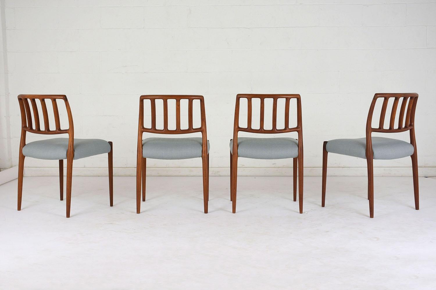 This set of six 1960s Mid-Century Modern dining room chairs is model 83 by Niels Otto Moller. The teak wood frames have a curved back with slatted accents and the original finish. The comfortable seats have been completely restored with new cushions