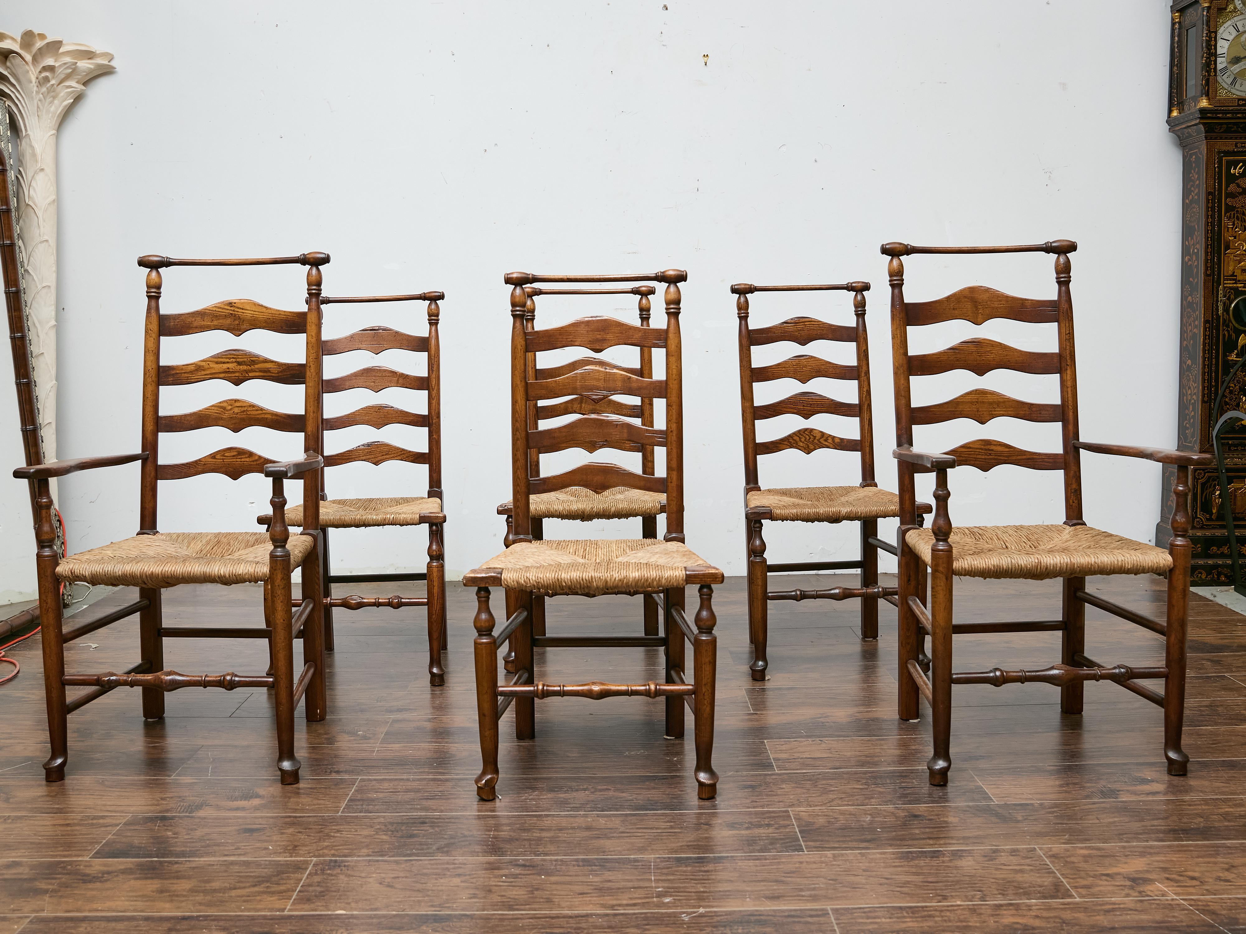 A set of six Midcentury ladder-back dining chairs with rush seats, comprising two armchairs and four side chairs, crafted in the traditional French provincial style. Made from warmly toned hardwood, each chair features four wavy horizontal back