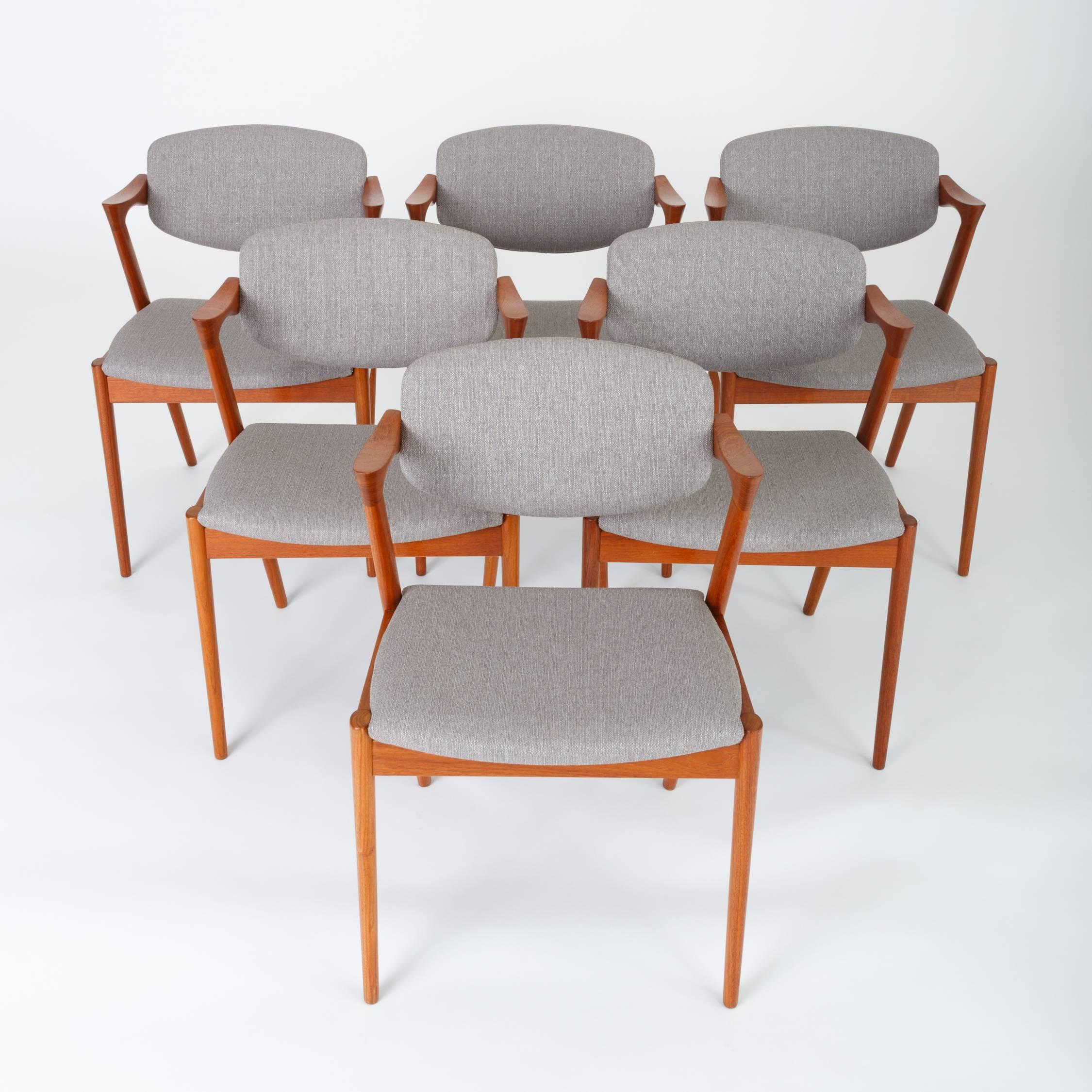 A set of six Danish modern teak dining chairs by Kai Kristiansen for Schou Andersen, with a sculpted frame and sharp lines. The model 42 chair was the first chair to with armrests supported by the rear legs of the frame, and was a critical darling