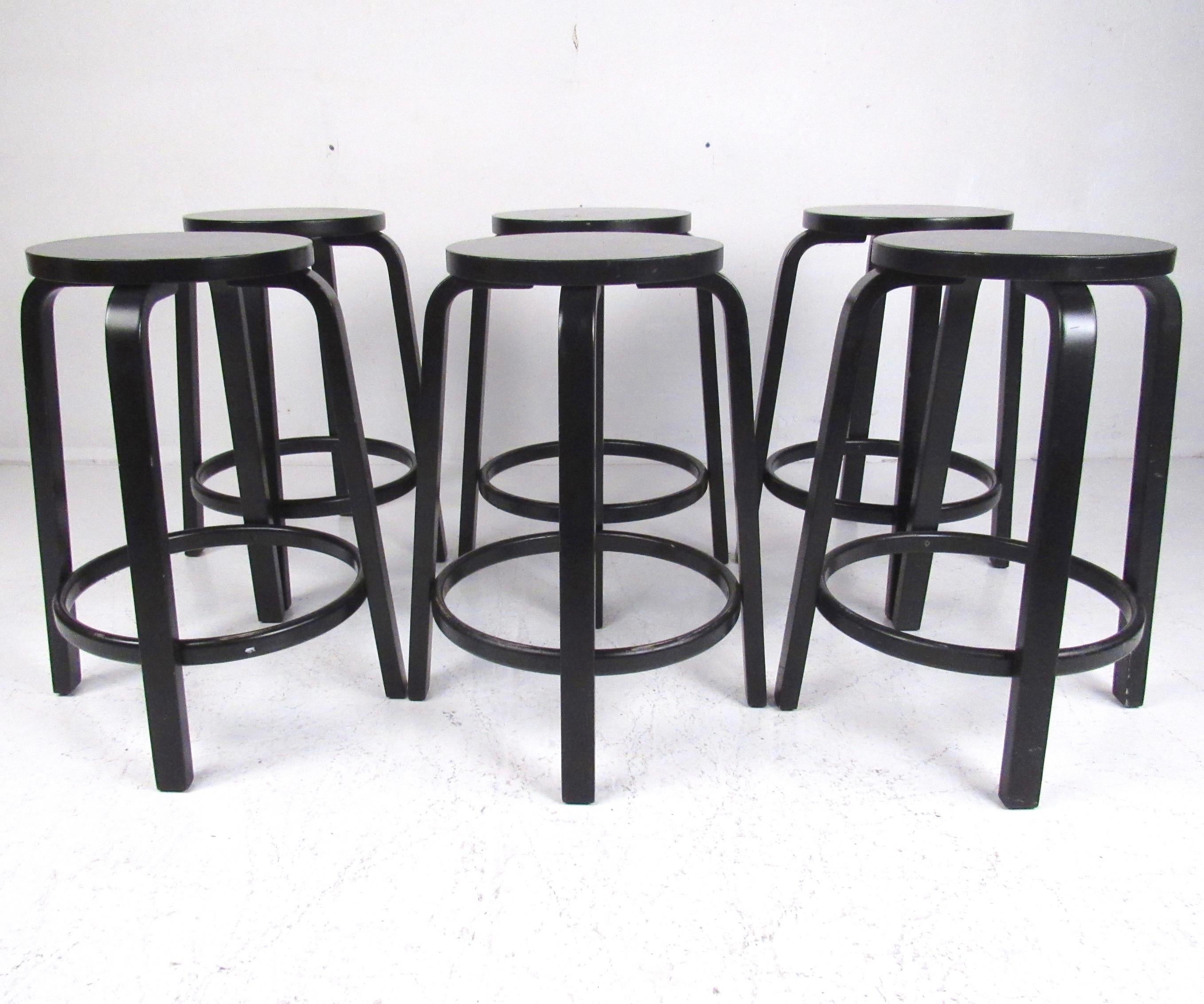 This stylish set of modern bar stools by Alvar Alto feature Italian design with ebonized finish for Artek, a contemporary manufacture of a Mid-Century Modern design. Bentwood legs and versatile seat height (26.75 inches) make this a sleek set of six