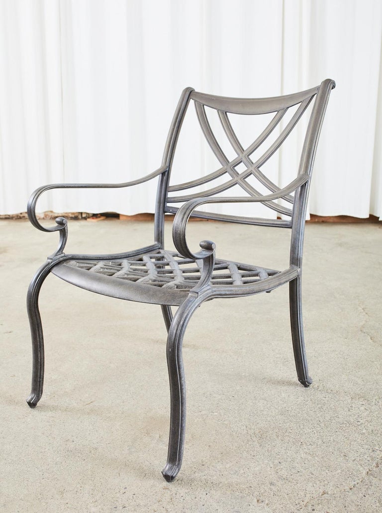 Stately set of six aluminum patio and garden dining armchairs made in the style and manner of Brown Jordan. The cast aluminum frames feature a square back with neoclassical style ribbon swag back splat. The generous seat has regency style hooked