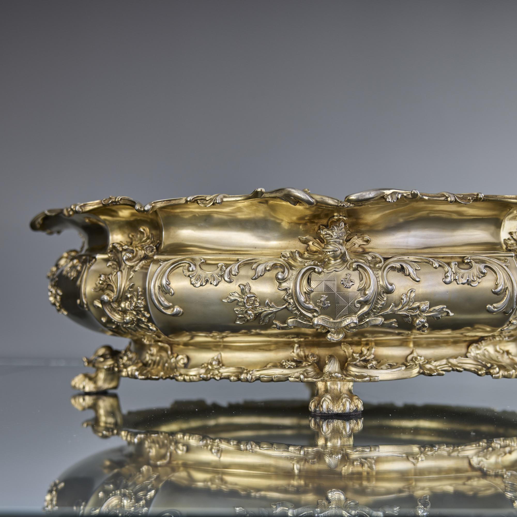 Superb-quality, oval and shaped antique silver-gilt wine cistern of substantial quality and weight resting on lion's paws feet. The body is of elongated shape with foliate and floral decoration around a Rococo revival cartouche featuring the arms of