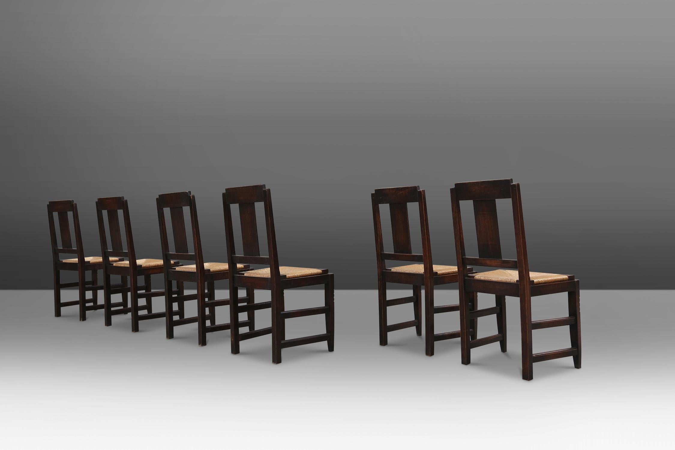 Set of six dining chairs by the french designer Victor Courtray made in the 1940's. Made of solid stained oak and a woven seat. Has some great geometrical details in the backrest and legs what gives this chairs the great Art Deco look.