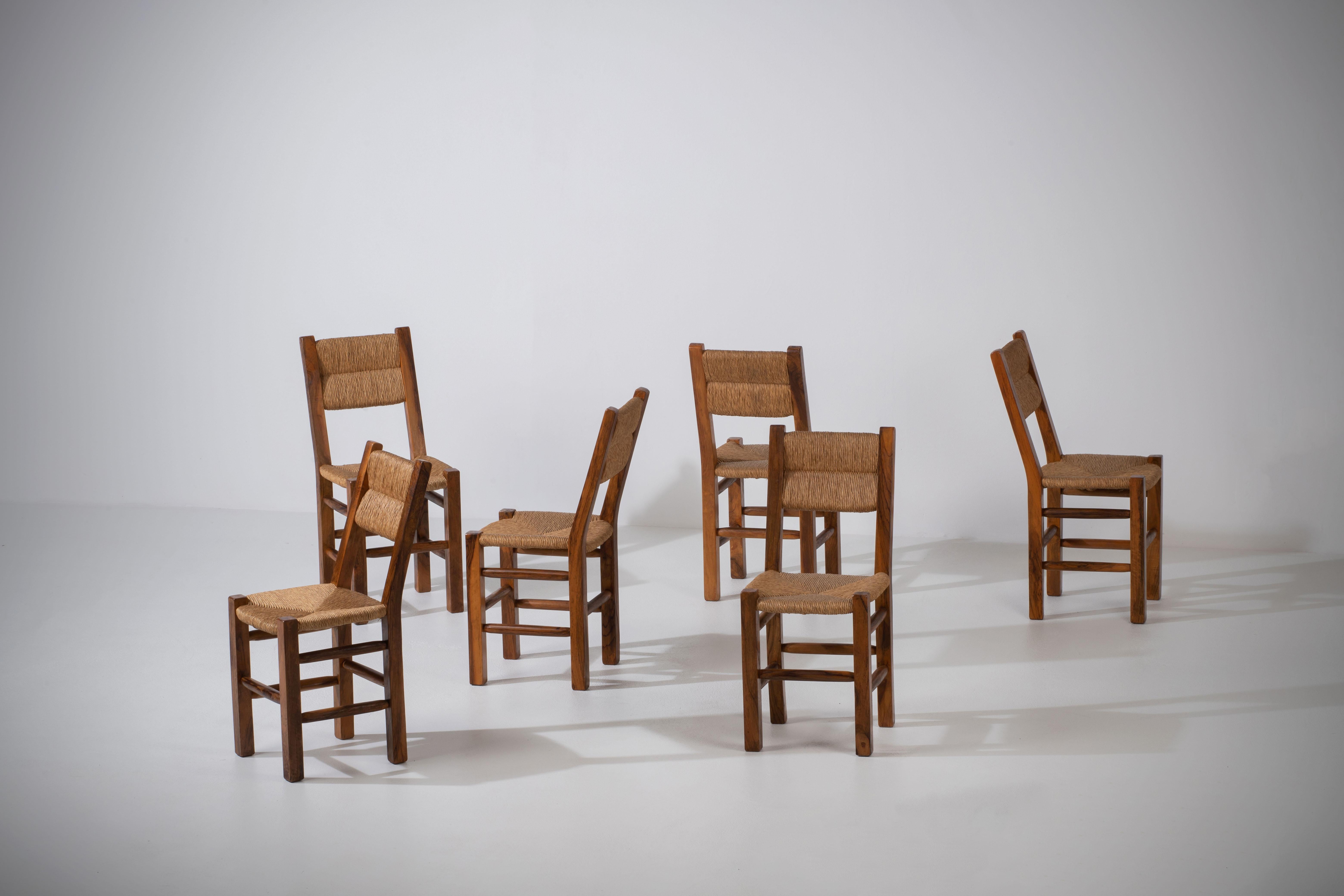 Introducing a stunning set of six mid-century chairs from France, crafted with a beautiful combination of olivewood and rush seating. These chairs pay homage to the influential works of renowned designers such as Charlotte Perriand and Adrien Audoux