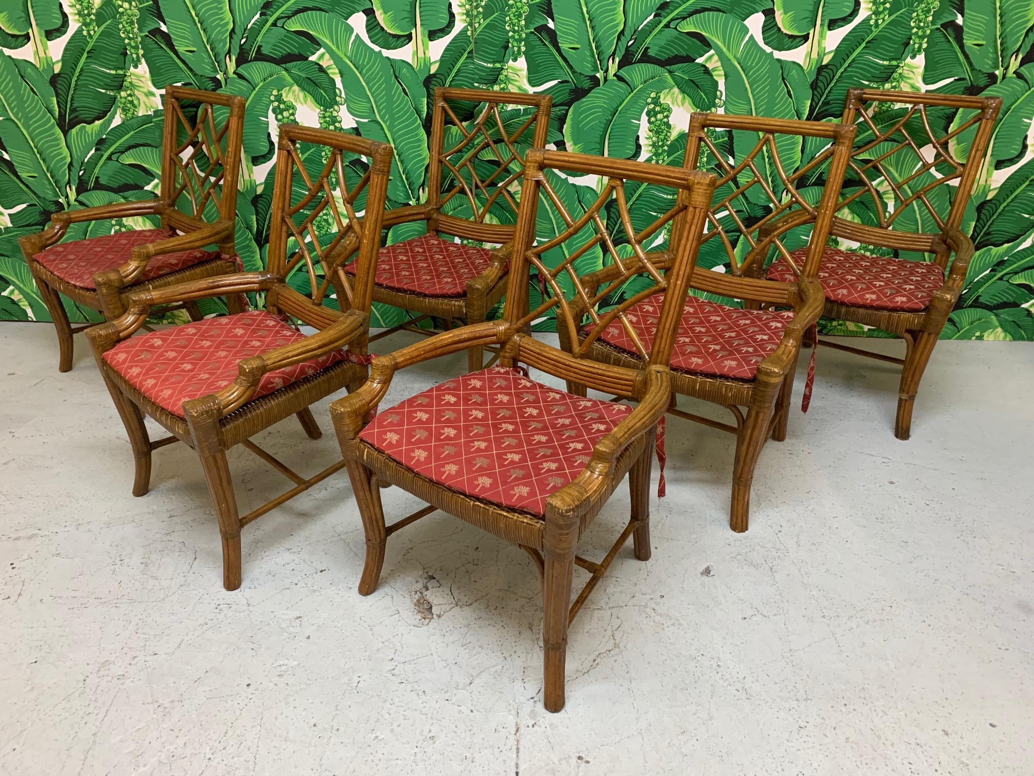 Set of 6 rattan dining chairs in Asian chinoiserie style. Wicker seats and leather wrapped joints. Seat cushions in a deep red with palm tree design. Good condition structurally and cosmetically showing marks consistent with age and use.
  
 