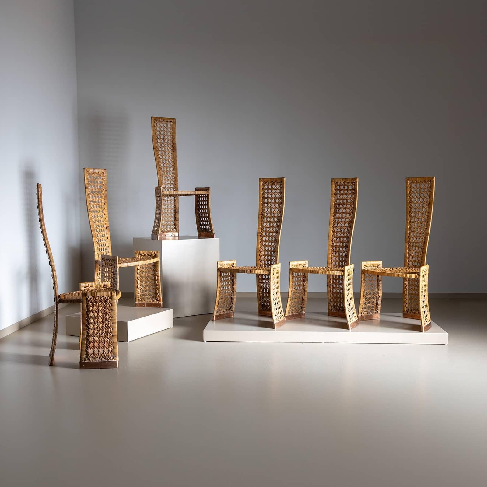Un ensemble de six chaises en rotin tressé, avec de hauts dossiers incurvés pour plus de confort. Les pieds ont été renforcés par des protections en cuivre pour une meilleure durabilité. Le motif de tissage complexe crée d'élégants éléments croisés