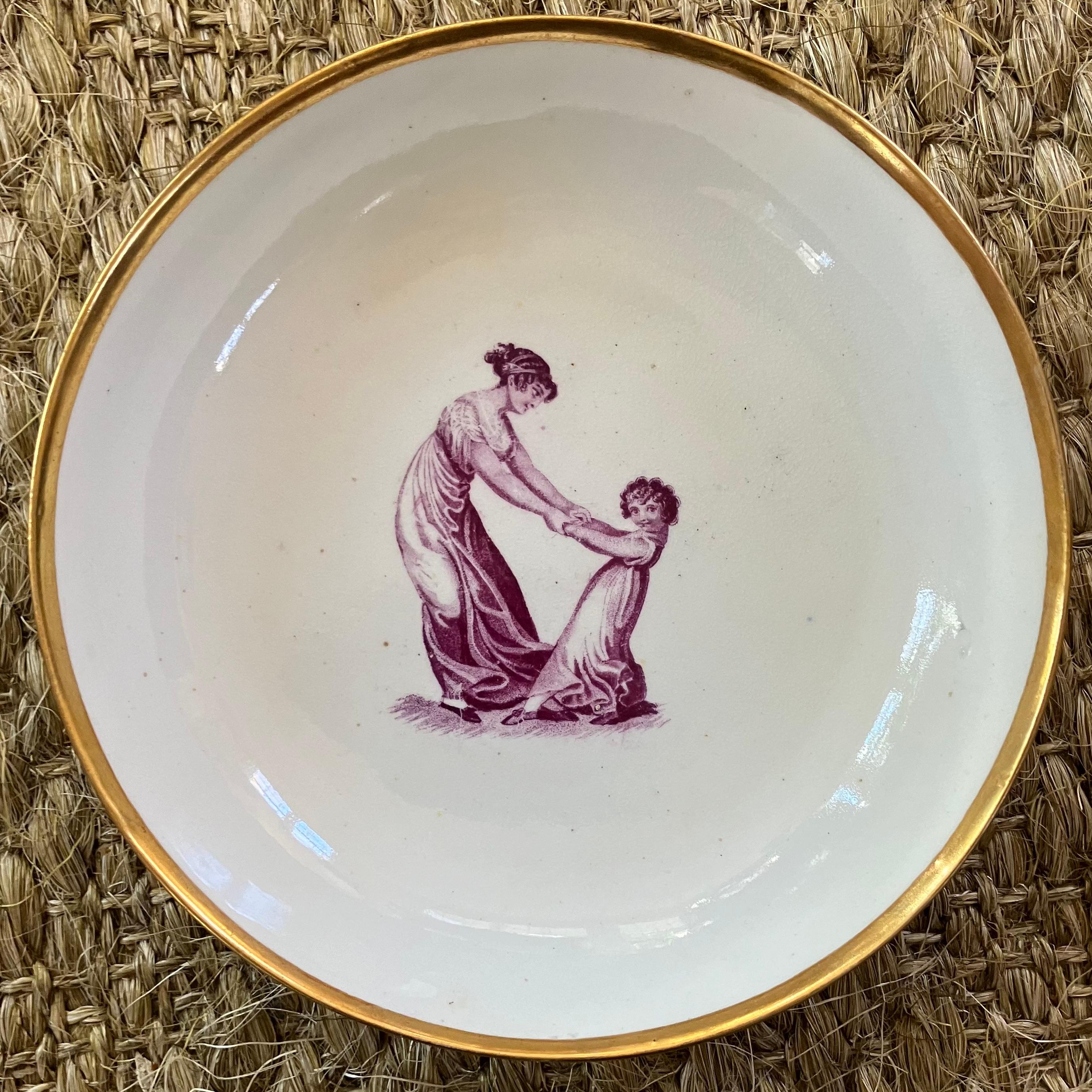 Set of six Regency porcelain cake plates. Six gilt rimmed circular dishes with Adam Buck Regency Period domestic scenes in puce/ magenta on lustrous English cream porcelain. England, 1810
Dimensions: 7.88