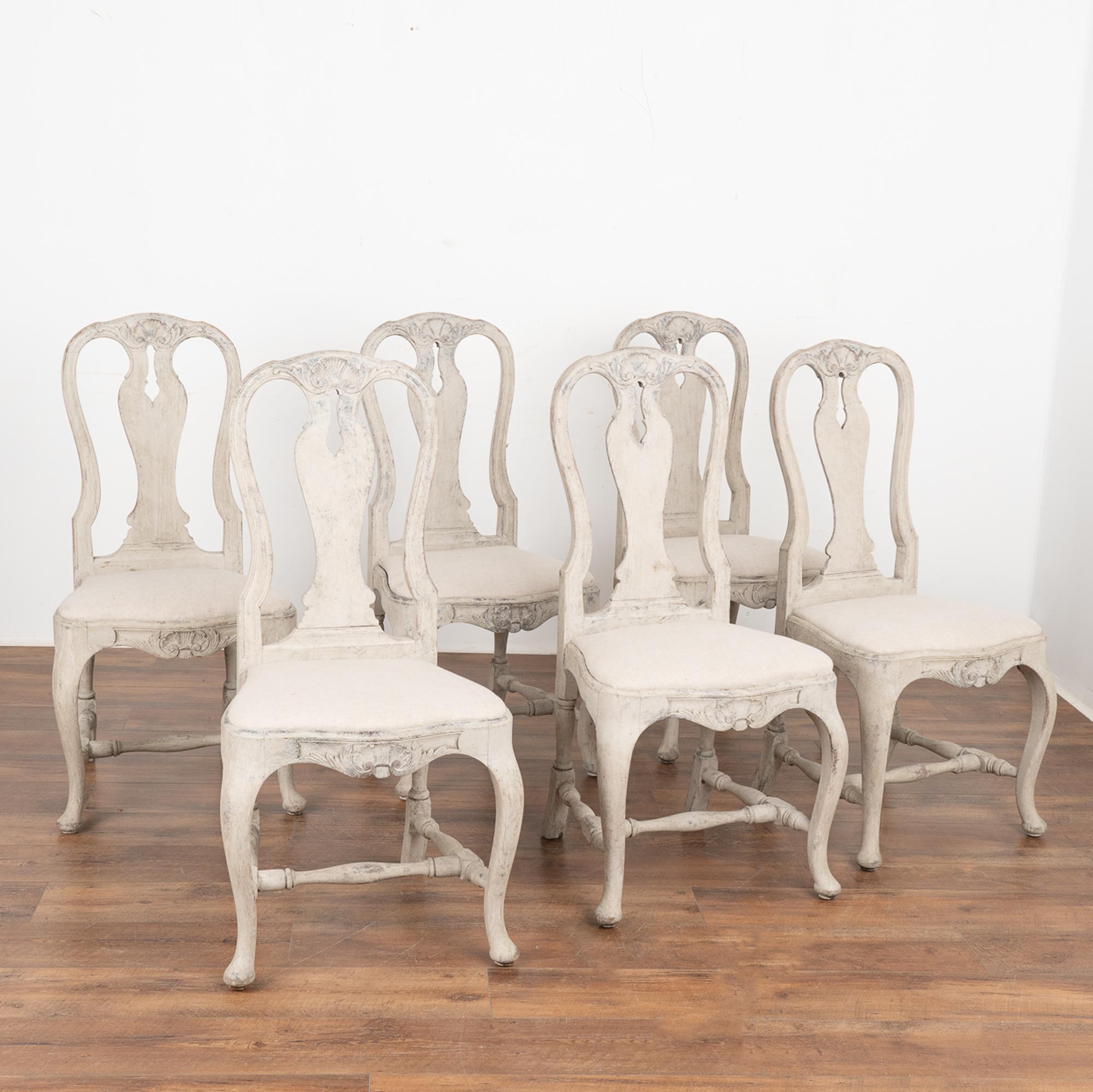 Set of 6 lovely Swedish rococo dining chairs with curved cabriolet legs and carved accents. 
Newer professionally applied layered gray painted finish has been lightly rubbed and perfectly distressed to fit the age and grace of these chairs.