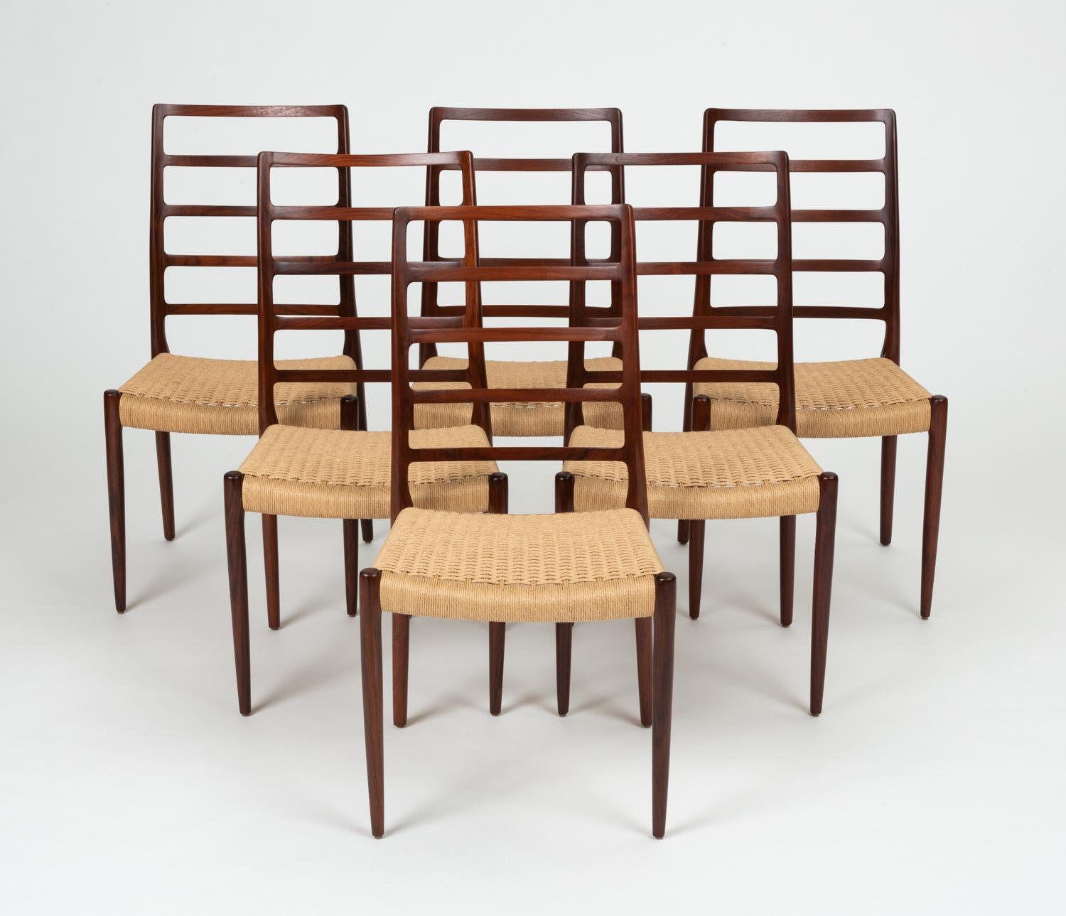 A set of six rosewood dining chairs designed by Niels Otto Møller in 1971 and manufactured by JL Møllers Møbelfabrik of Denmark with Danish paper cord seats. The Model 82 chairs have a tall ladder back with five horizontal supports; the solid wood