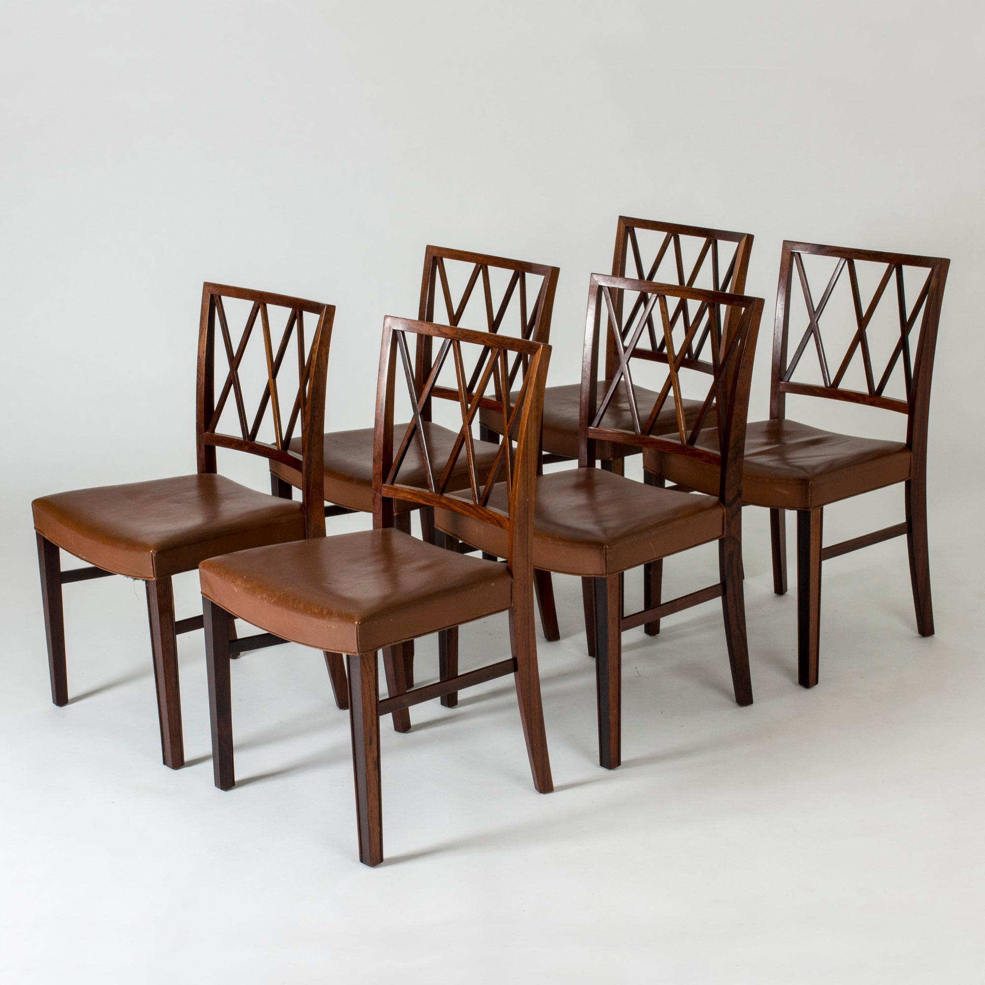 Set of four beautiful dining chairs by Ole Wanscher. Made from rosewood with striking backs with a crossed pattern. Brown leather seats.