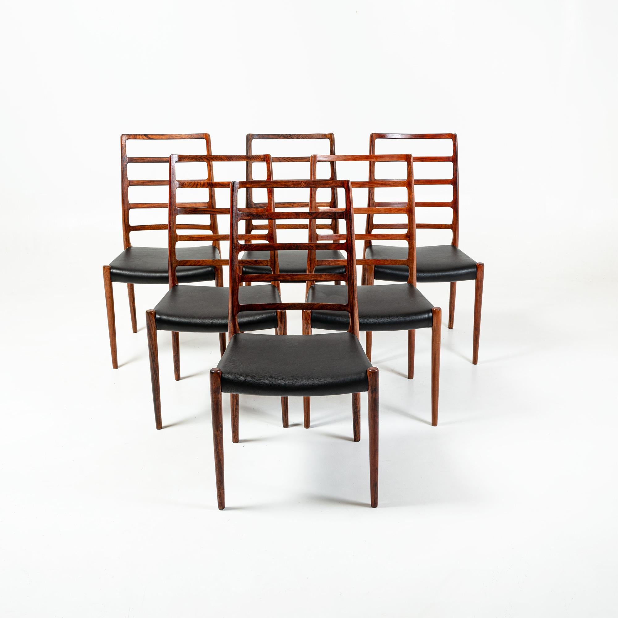 Rare et iconique ensemble de 6 chaises de salle à manger en bois de rose conçues par Niels Otto Moller pour JL Møller Møbelfabrik en 1954. L'ensemble a été entièrement restauré, avec un siège en cuir noir entièrement neuf.