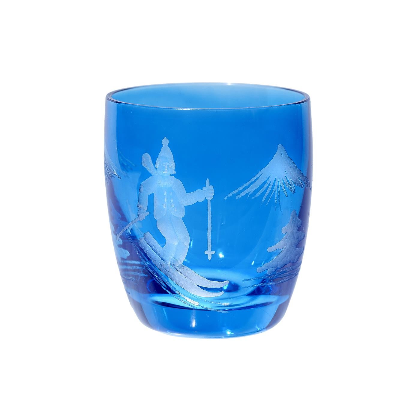 Set di sei bicchieri da grappa soffiati a mano in cristallo blu con decoro di uno sciatore inciso a mano. L'arredamento è una scena in stile country, con un ragazzo sciatore, alberi e montagne. Ti consigliamo di lavarti a mano.