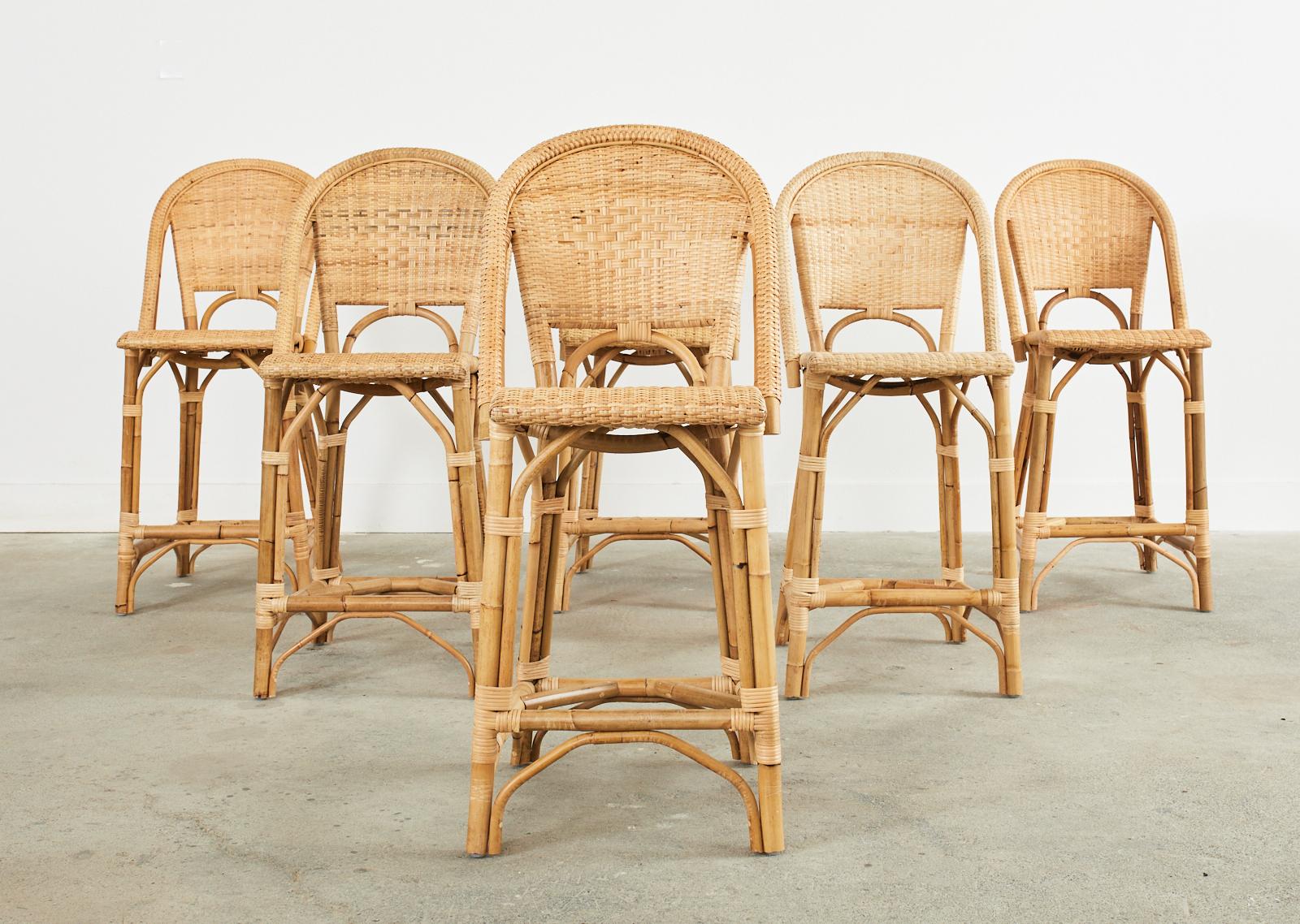 Charming set of six Parisian style bistro cafe barstools crafted from rattan and woven wicker by Serena and Lily. Made in the organic modern style featuring gracefully bent rattan frames covered with woven wicker in a natural rattan finish. Near new