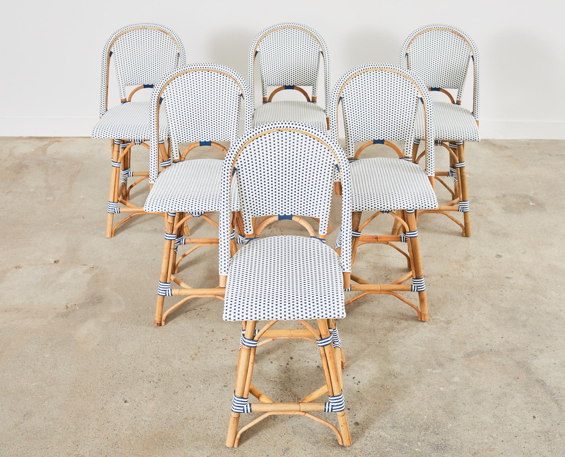 Charming set of six Parisian bistro cafe-style counter height bar stools by Serena and Lily. The attractive set features organic modern natural rattan frames bent by hand with woven resin seats. Each chair has a swivel seat in a nautical blue and