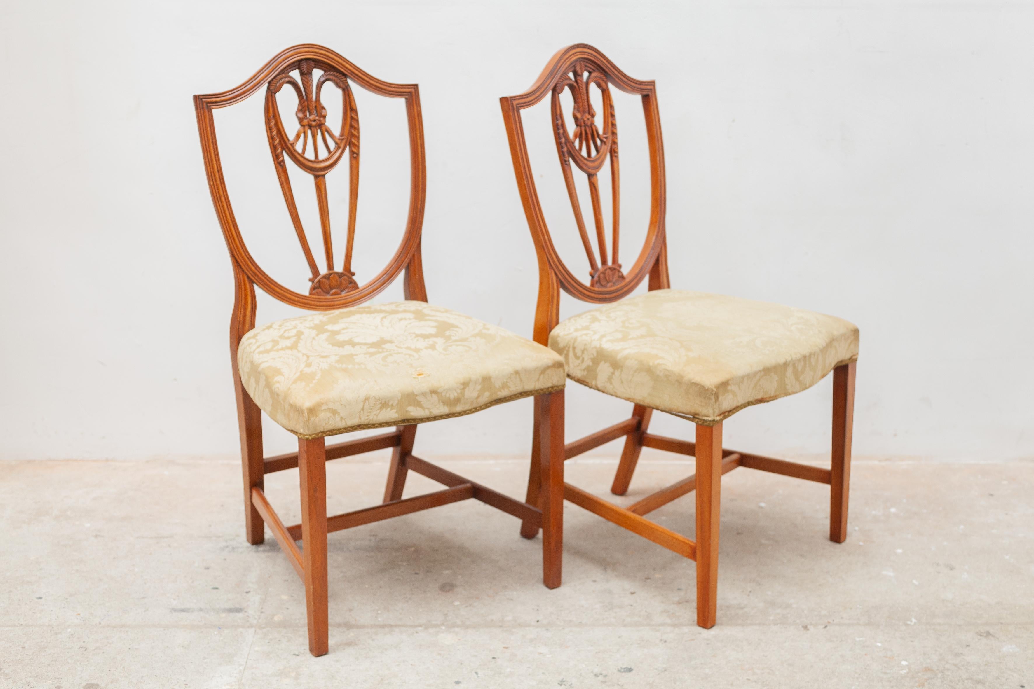 Dieser schöne Satz von sechs Stühlen im Georges-3-Stil aus massivem Satinholz zeichnet sich durch eine Rückenlehne mit zentralem Weizengarbenmuster im Hepplewhite-Stil aus. Sie haben goldfarbene gepolsterte Sitze und stehen auf spatenförmigen