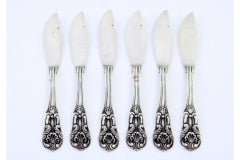 Set of six silver butter knives with reliefs and grooves along the handles