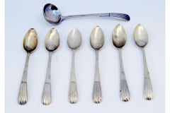 Set of six silver coffee spoons and sugar shovel with reliefs on the handles