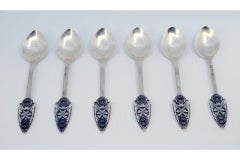Ensemble de six cuillères à dessert en argent avec applications et reliefs sur les manches.