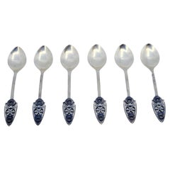 Set of six silver dessert spoons with applications and reliefs on the handles